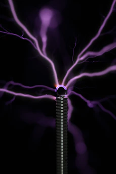 Purple electrical arcs radiating from the top of a metal coil
