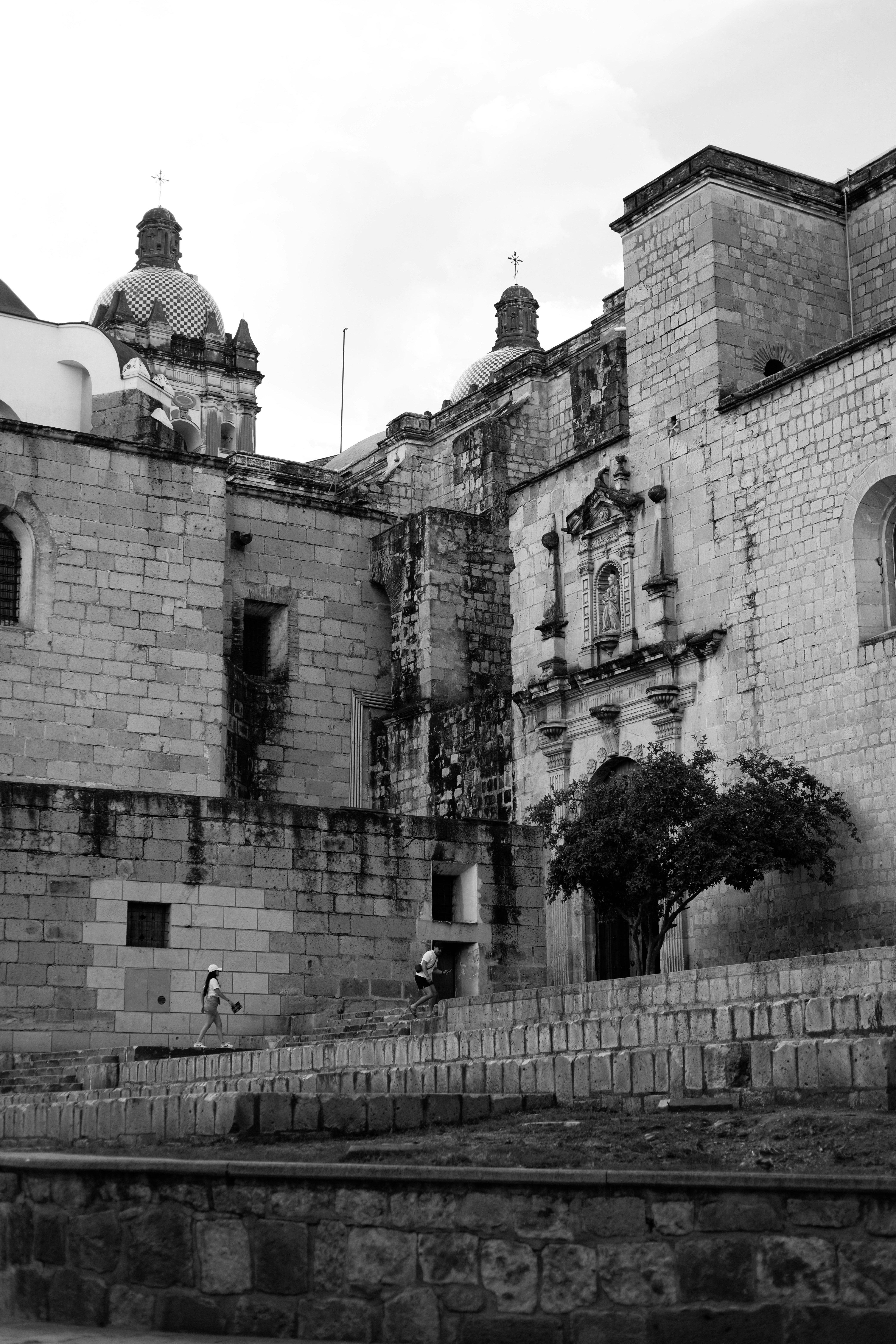 Dos personas caminando por escalones de piedra frente a una iglesia histórica de piedra