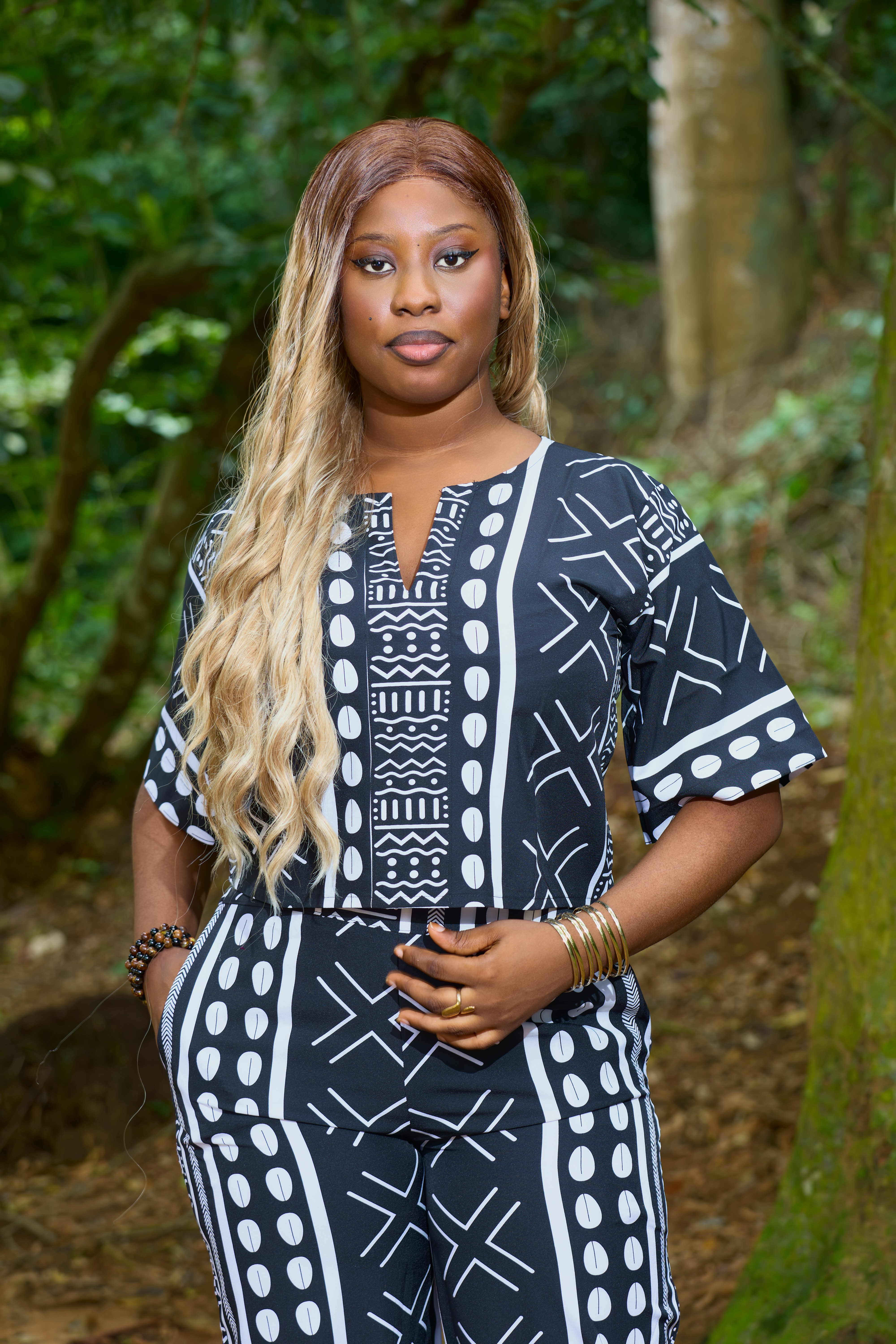 A woman with long blonde hair wearing a black and white patterned outfit outdoors