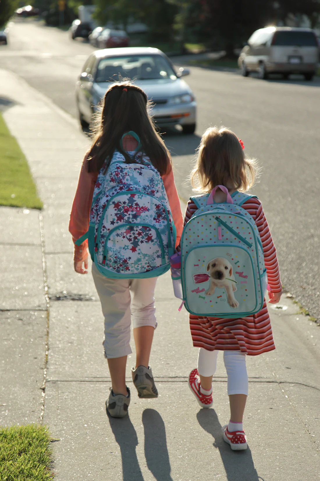 Duas crianças com mochilas caminhando para a escola