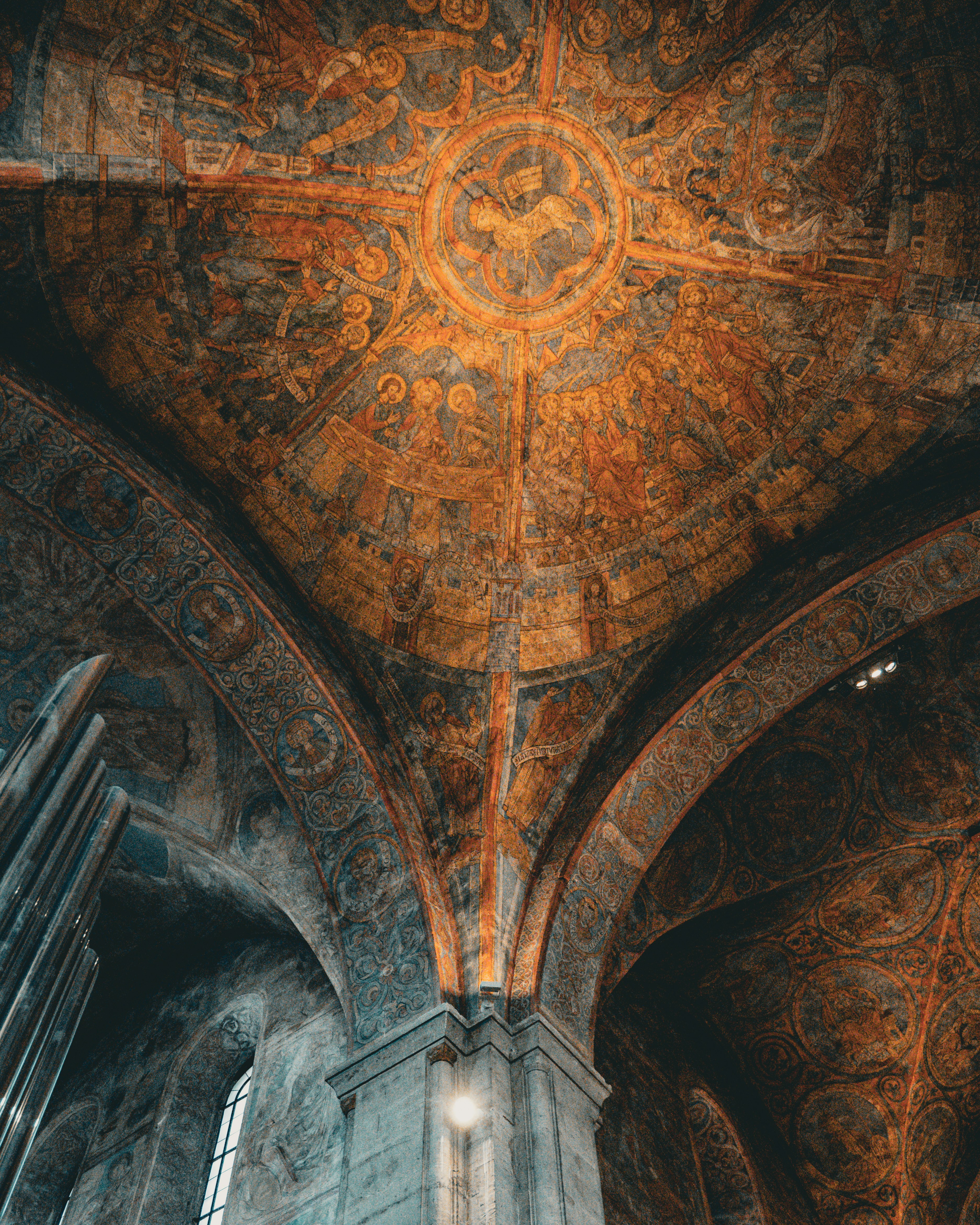 Ornate religious frescoes covering the vaulted ceiling and stone arches of a cathedral