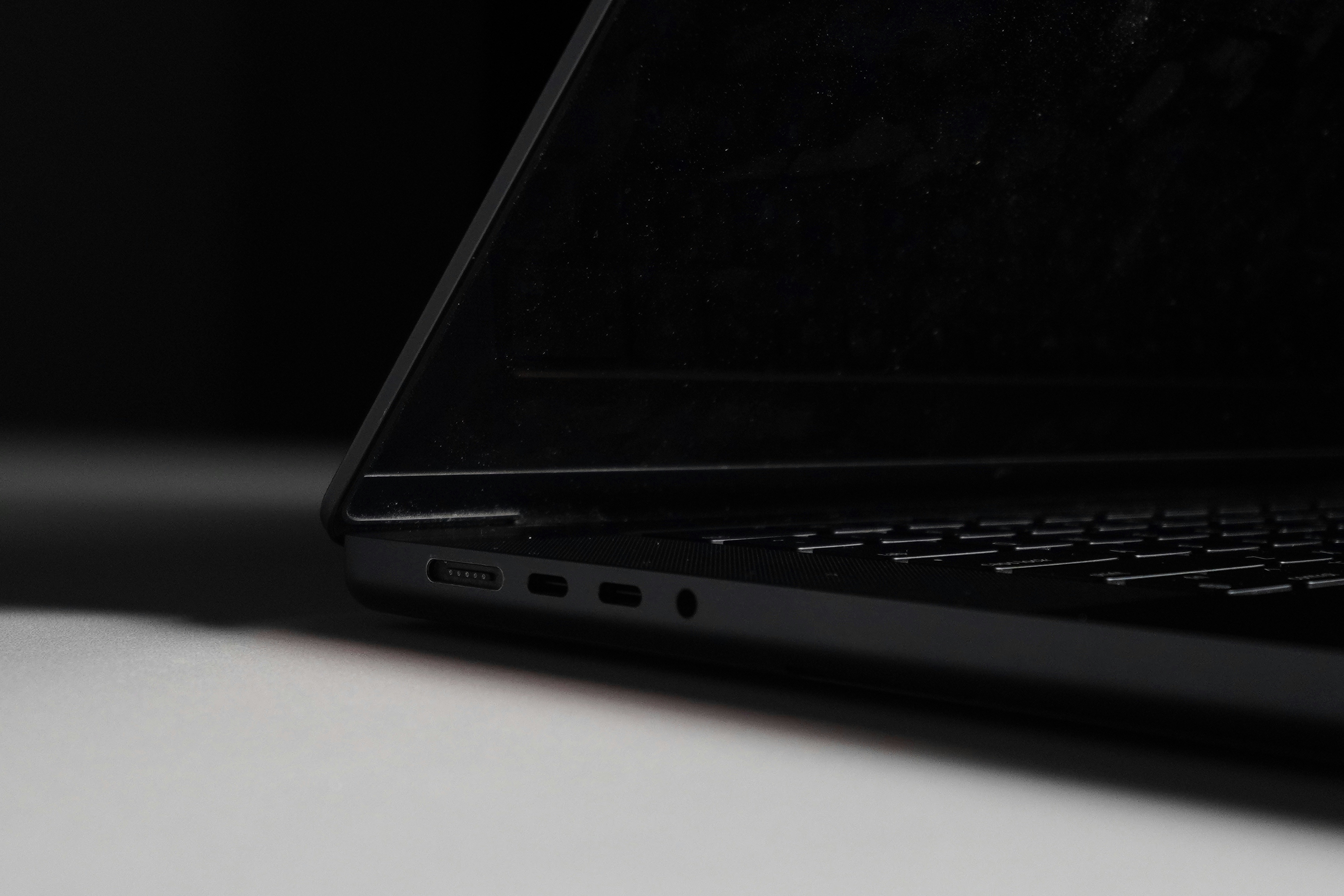 A black laptop with visible ports on the side on a white surface