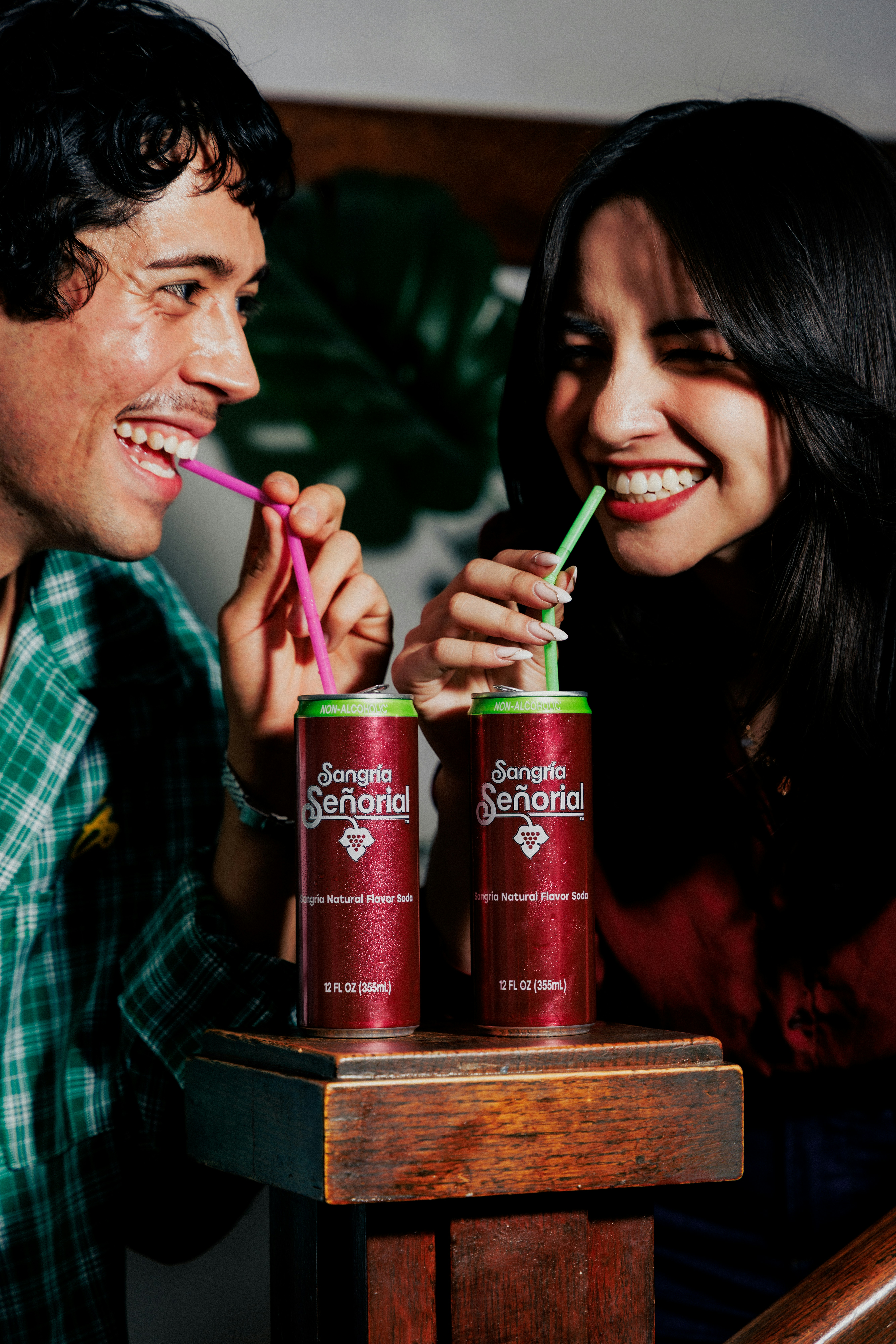 A man and a woman laughing while drinking from cans of Sangria Señorial
