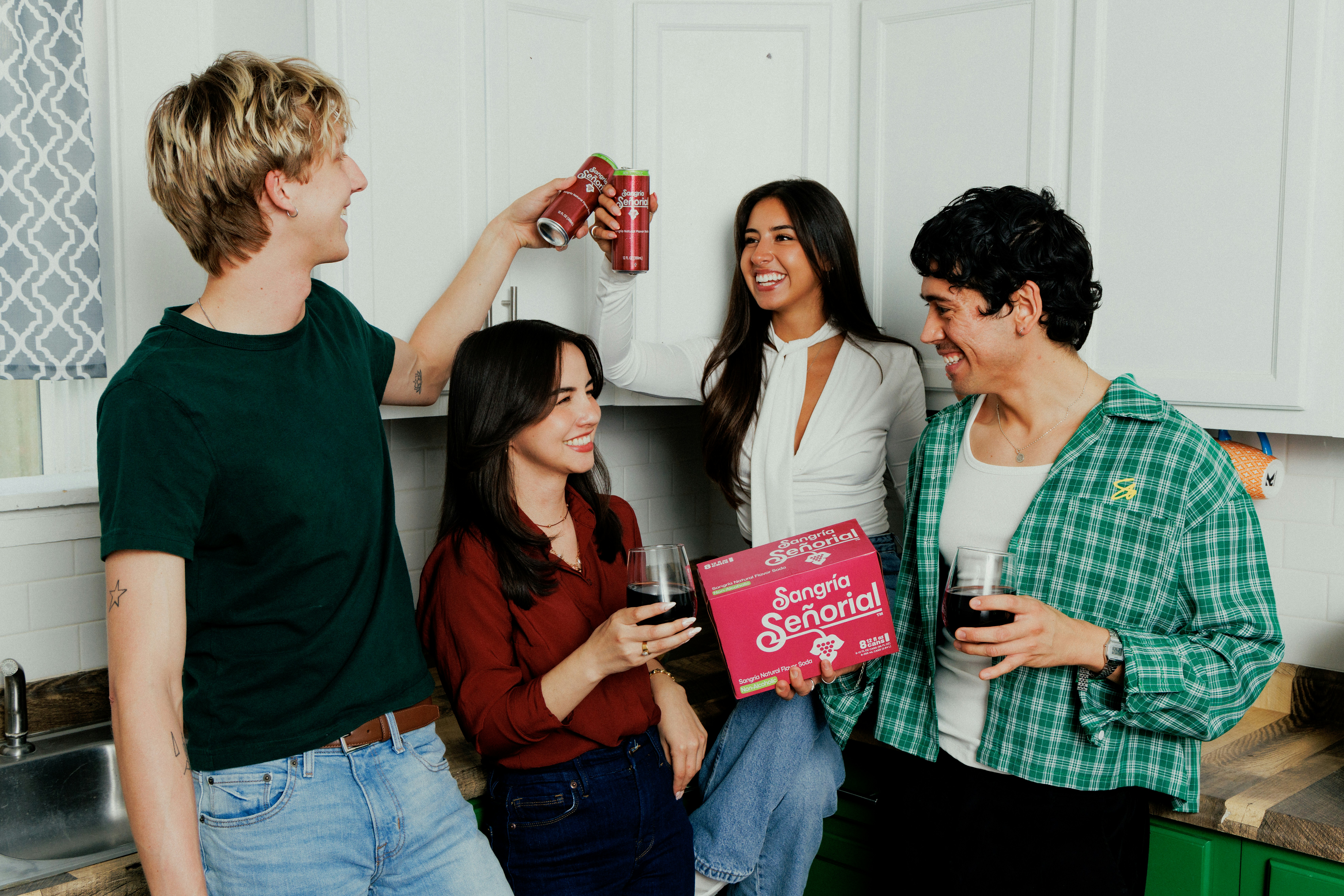 friends gathered around a laptop at a kitchen table, planning a social event, warm morning light, coffee cups nearby