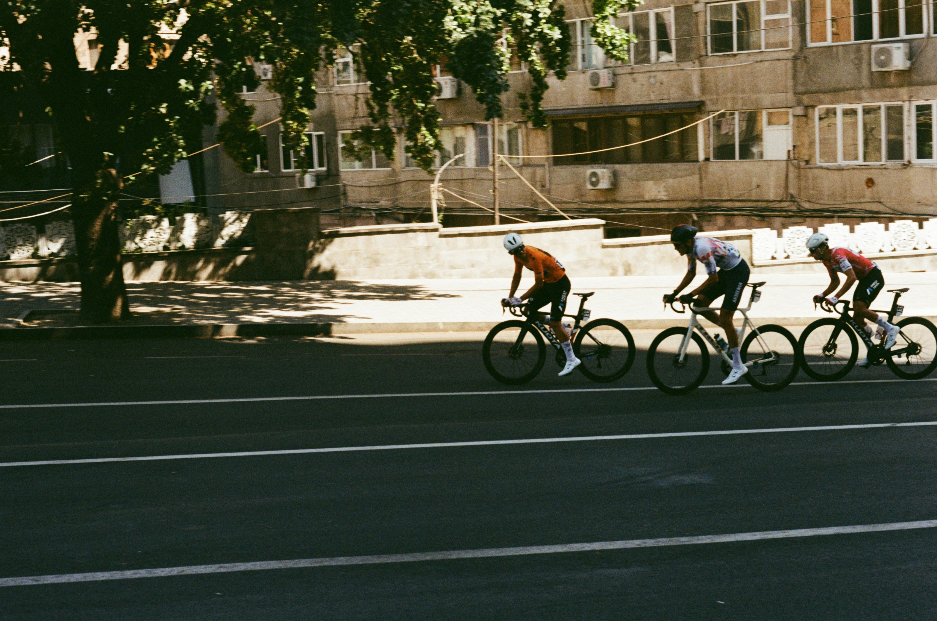 Three cyclists riding road bikes along a street