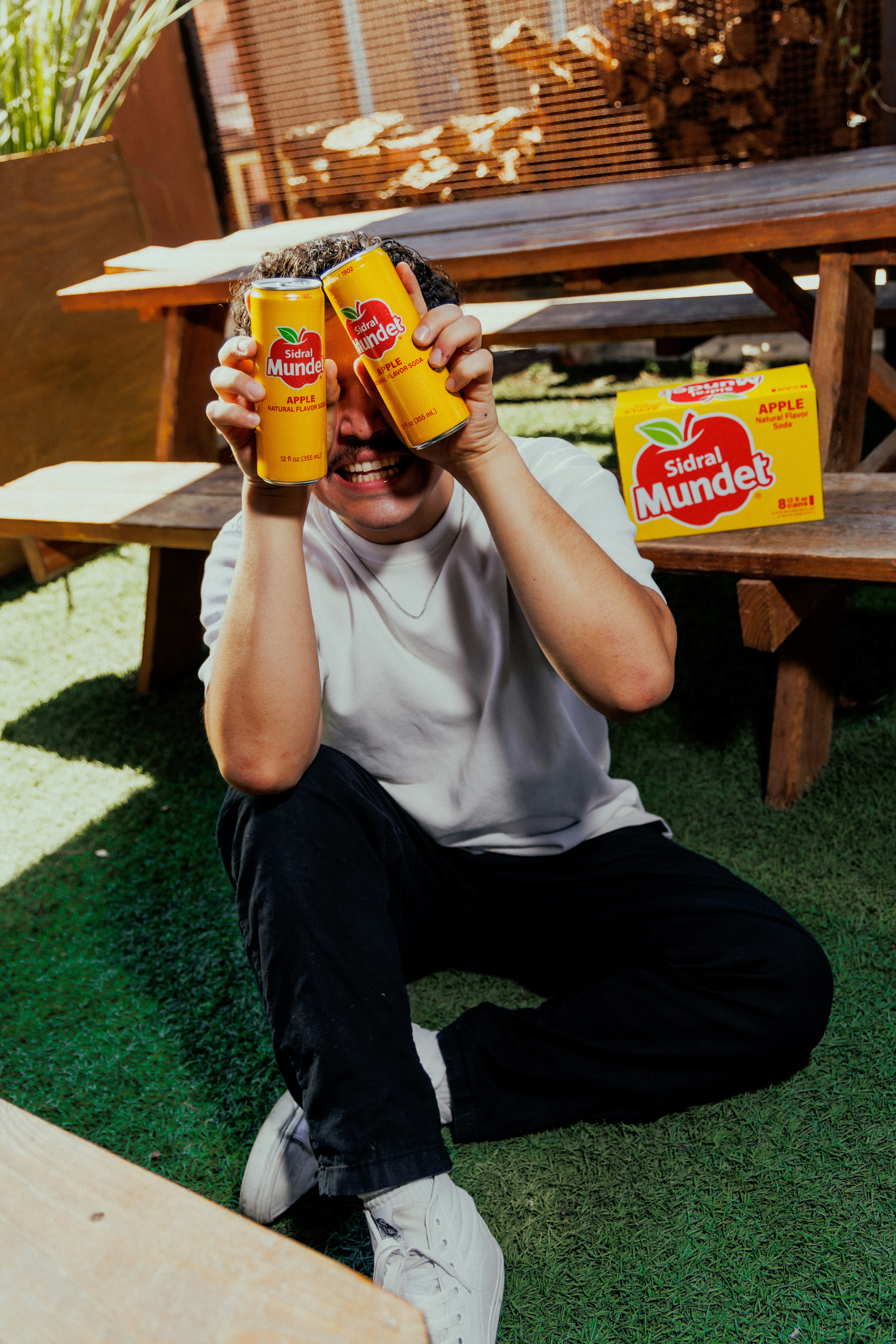 A person holding two yellow apple soda cans in front of their eyes
