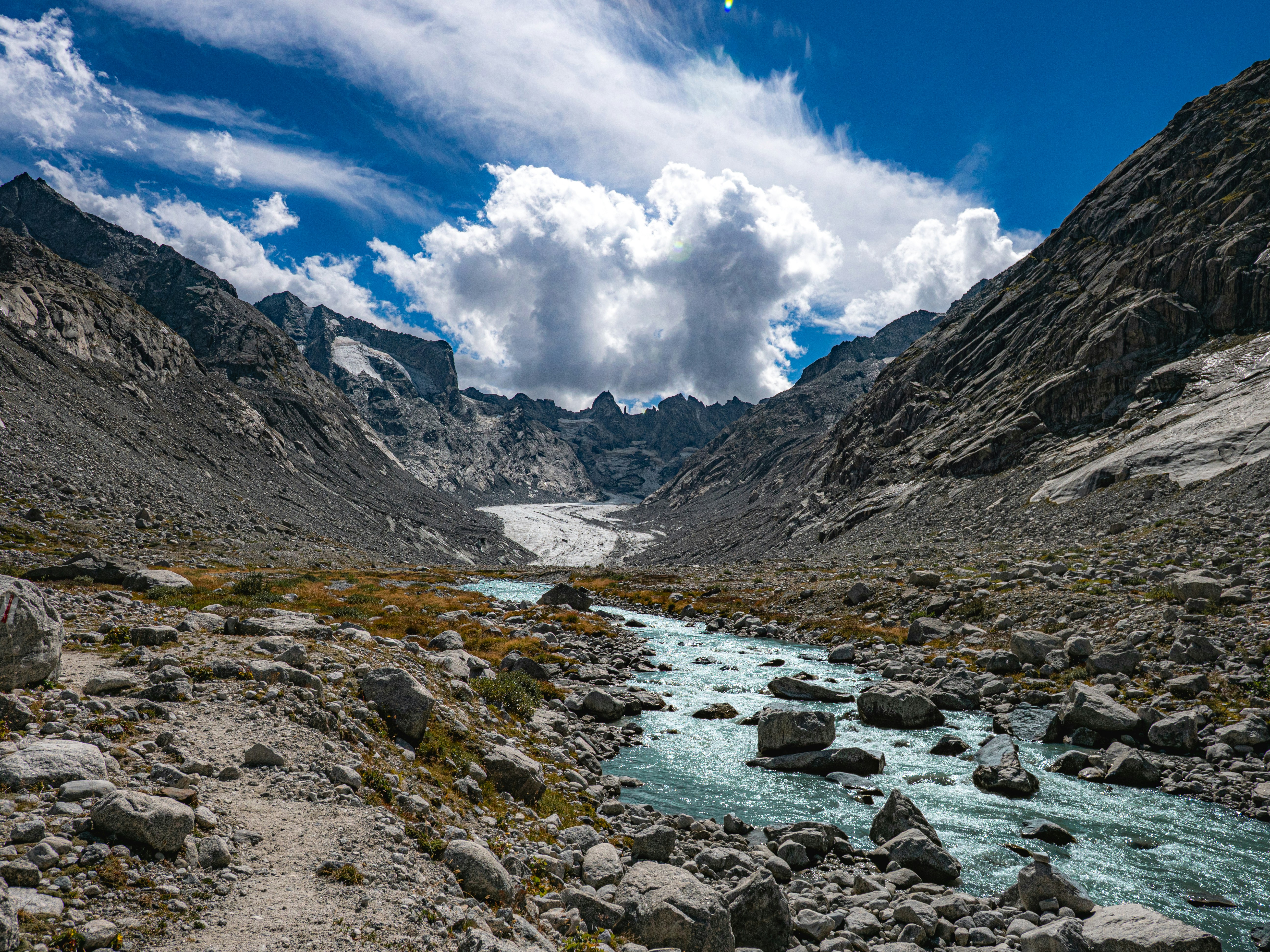 A glacial stream flowing through a rocky valley toward a distant glacier