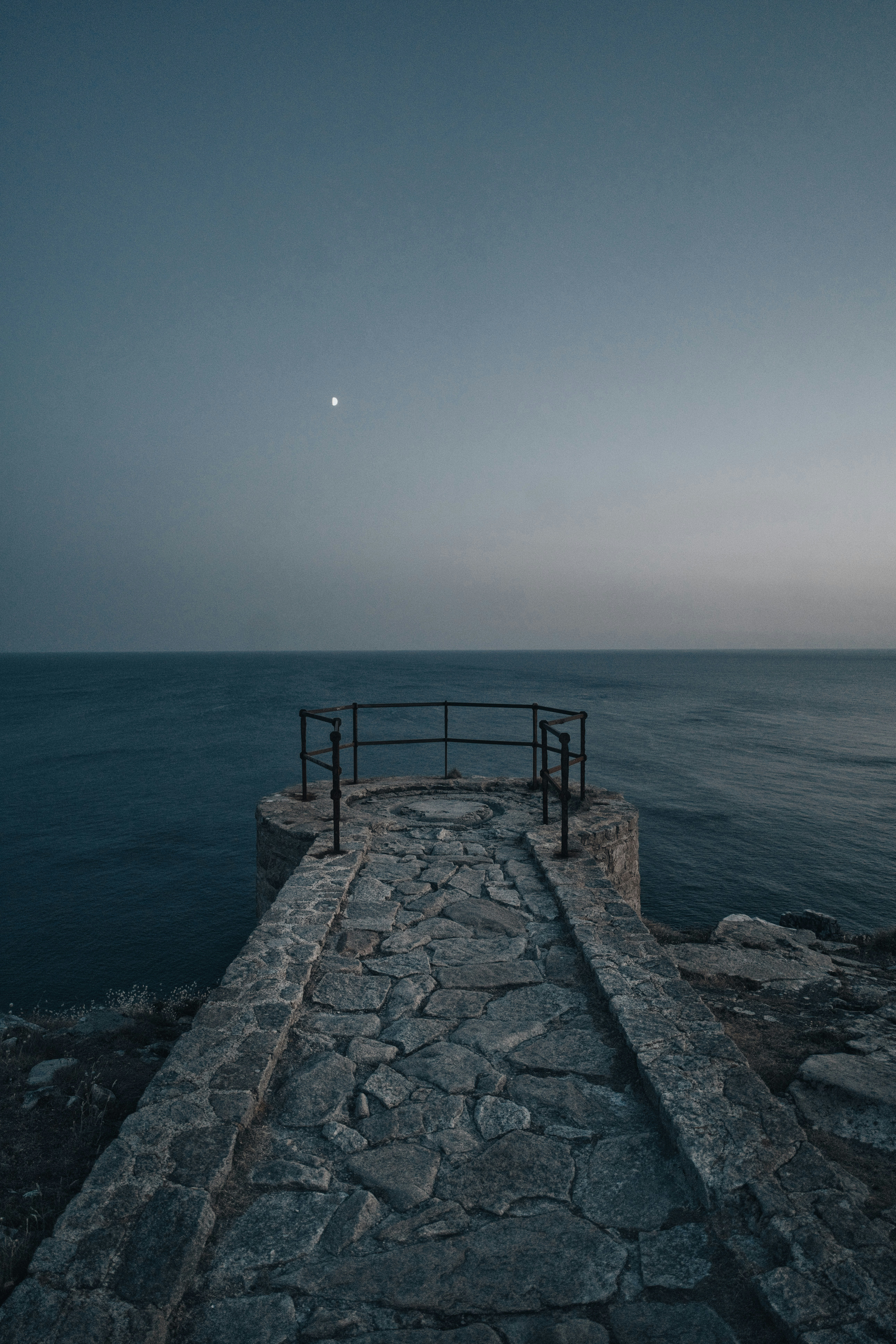 A stone walkway leading to a railed observation platform above the dark sea - 相关推荐
