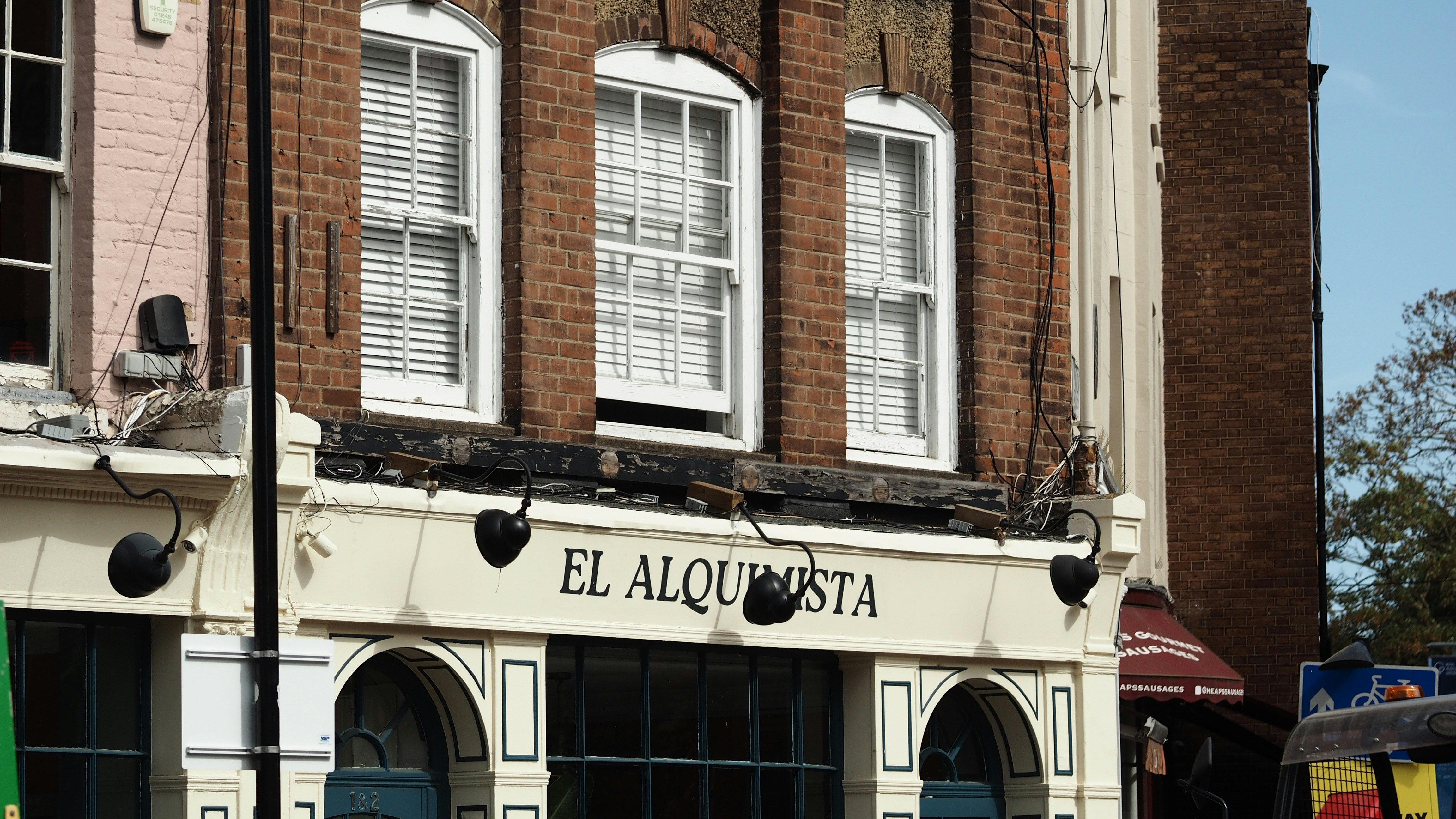 The storefront of El Alquimista with brick upper floors and white window frames
