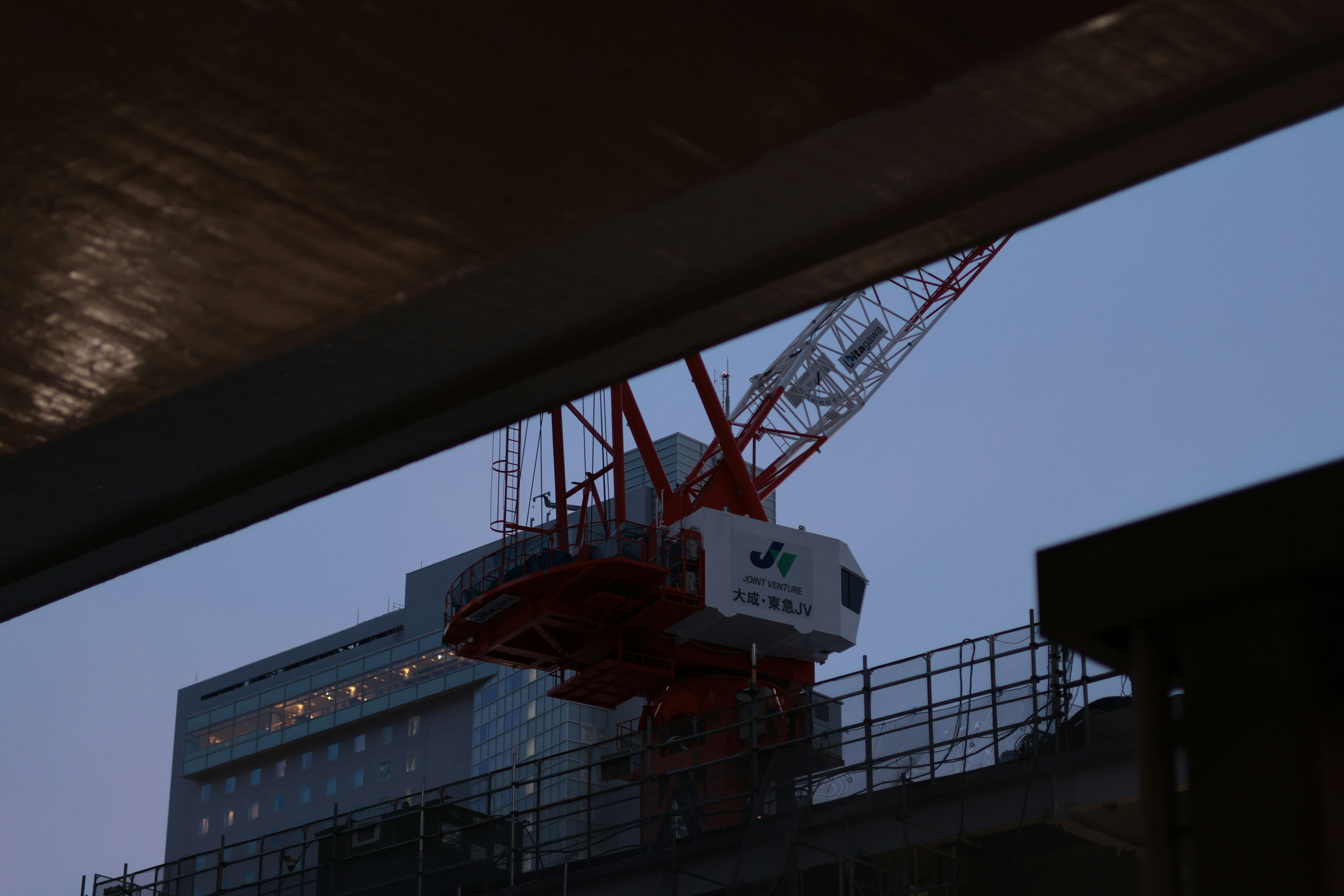 A red construction crane against a blue sky above a building under construction