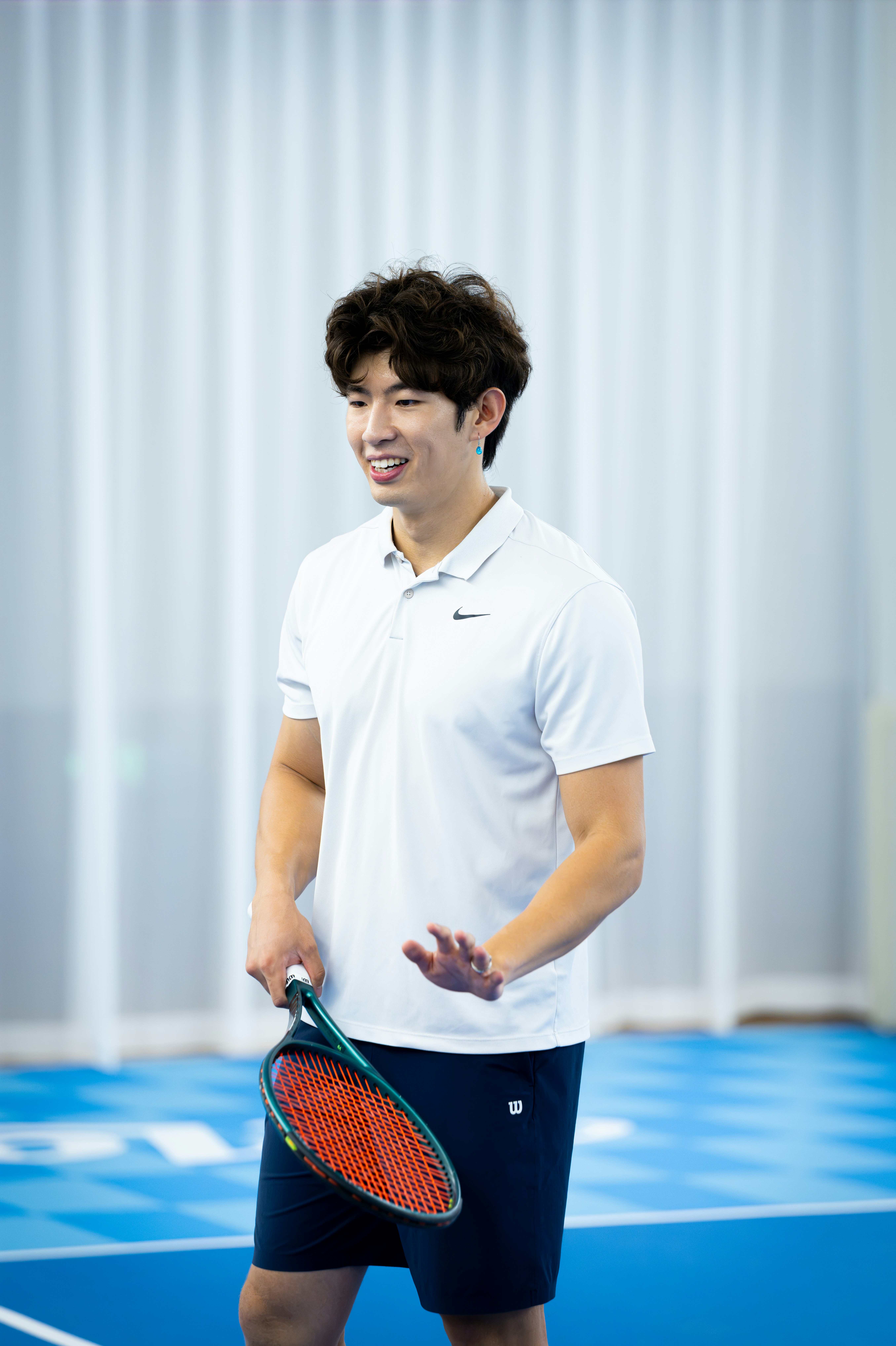 A man in a white polo shirt holding a tennis racket on a court
