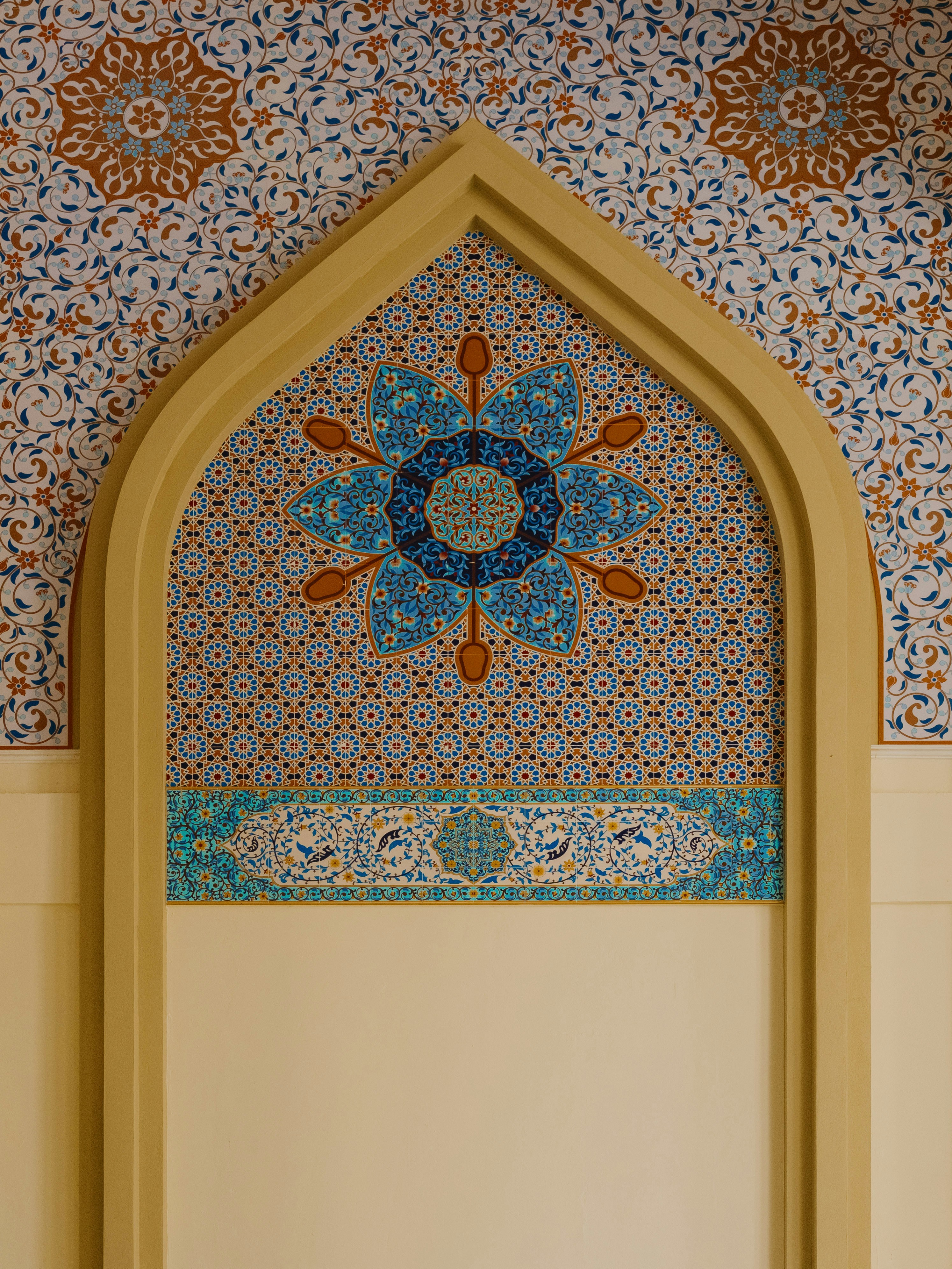 An arched wall niche decorated with intricate blue and orange floral tile patterns