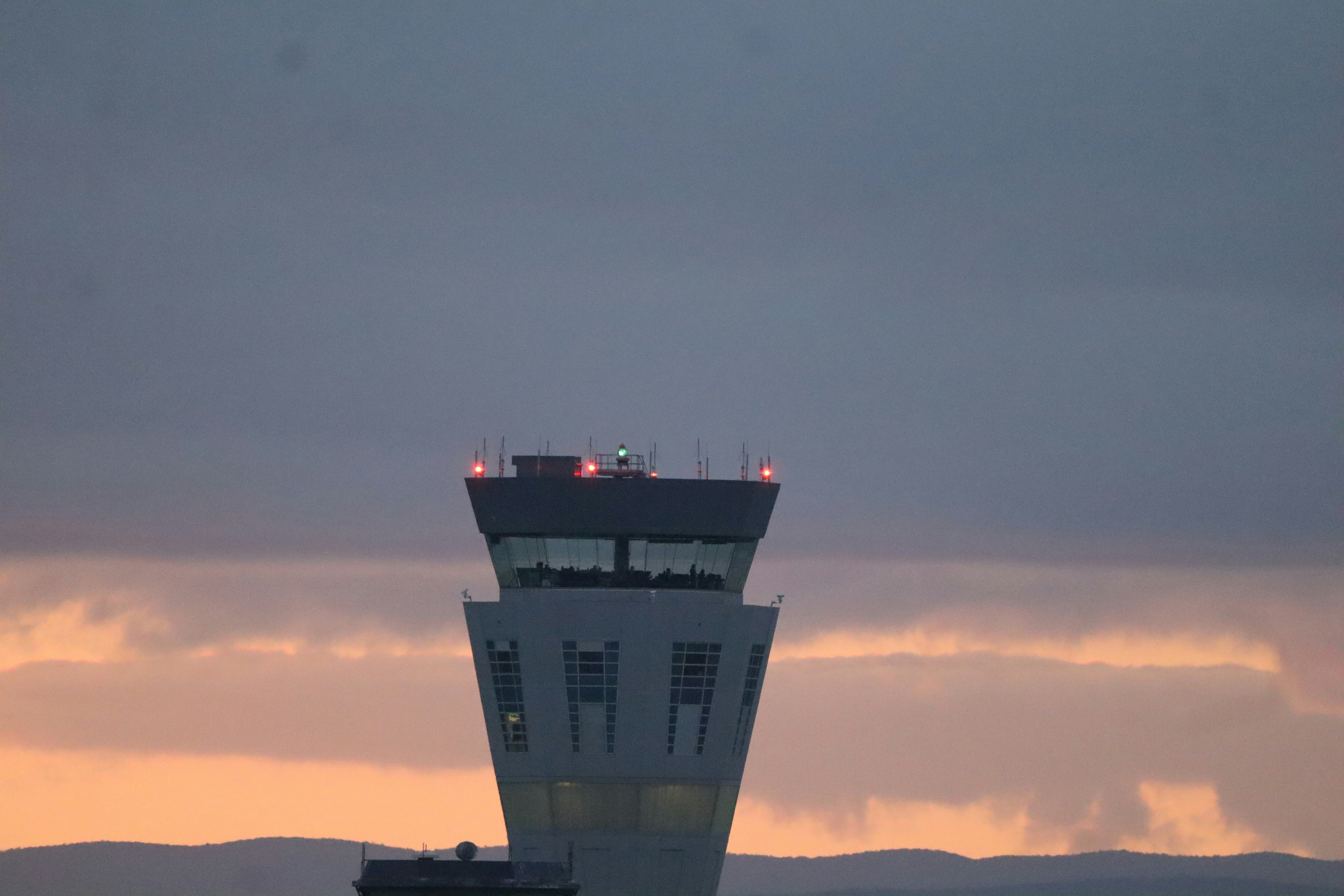 An airport control tower with red warning lights against a warm orange sky, for a story on Nuremberg Airport's closure.