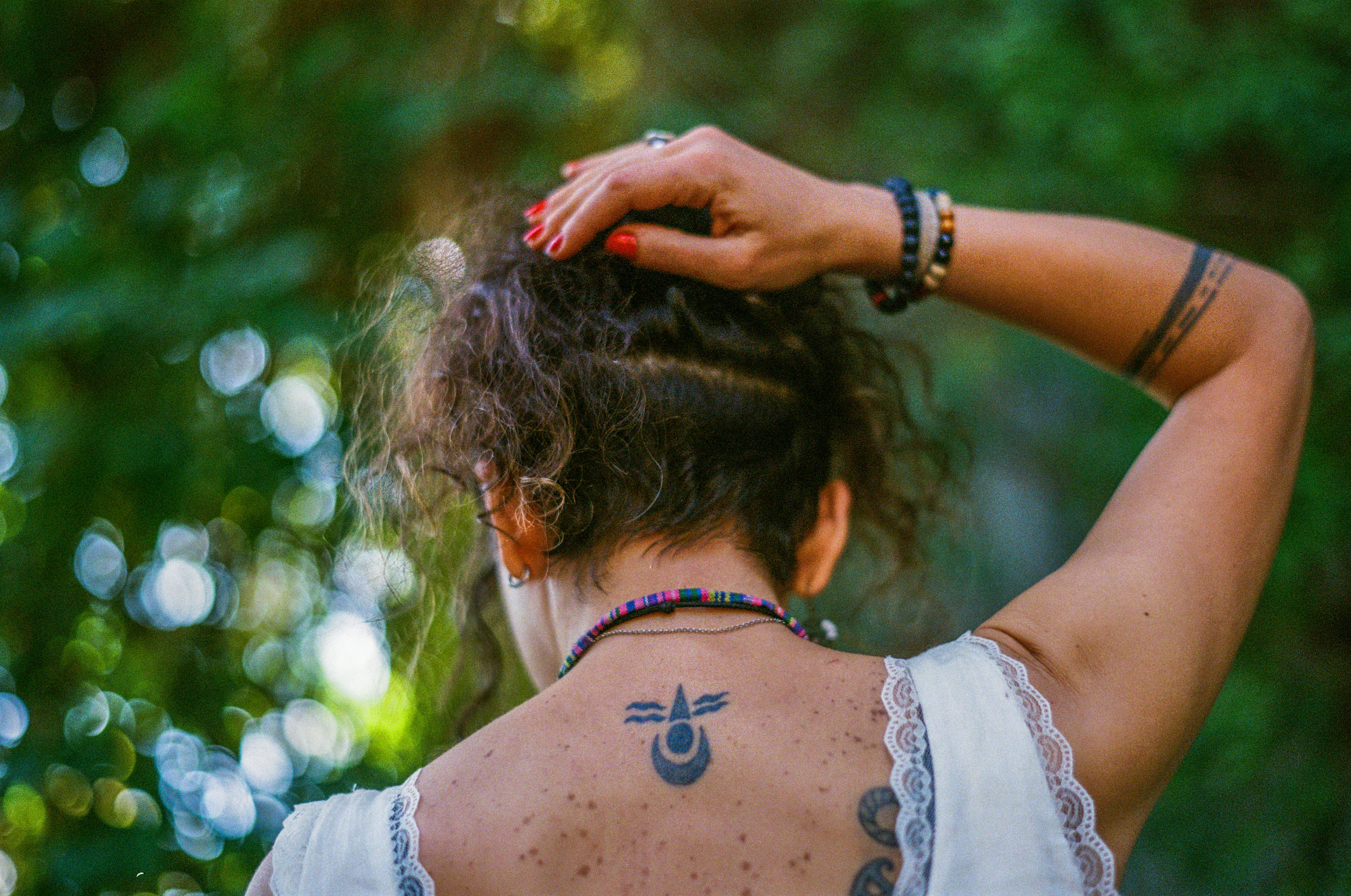 A person with a neck tattoo and red nail polish in a white top