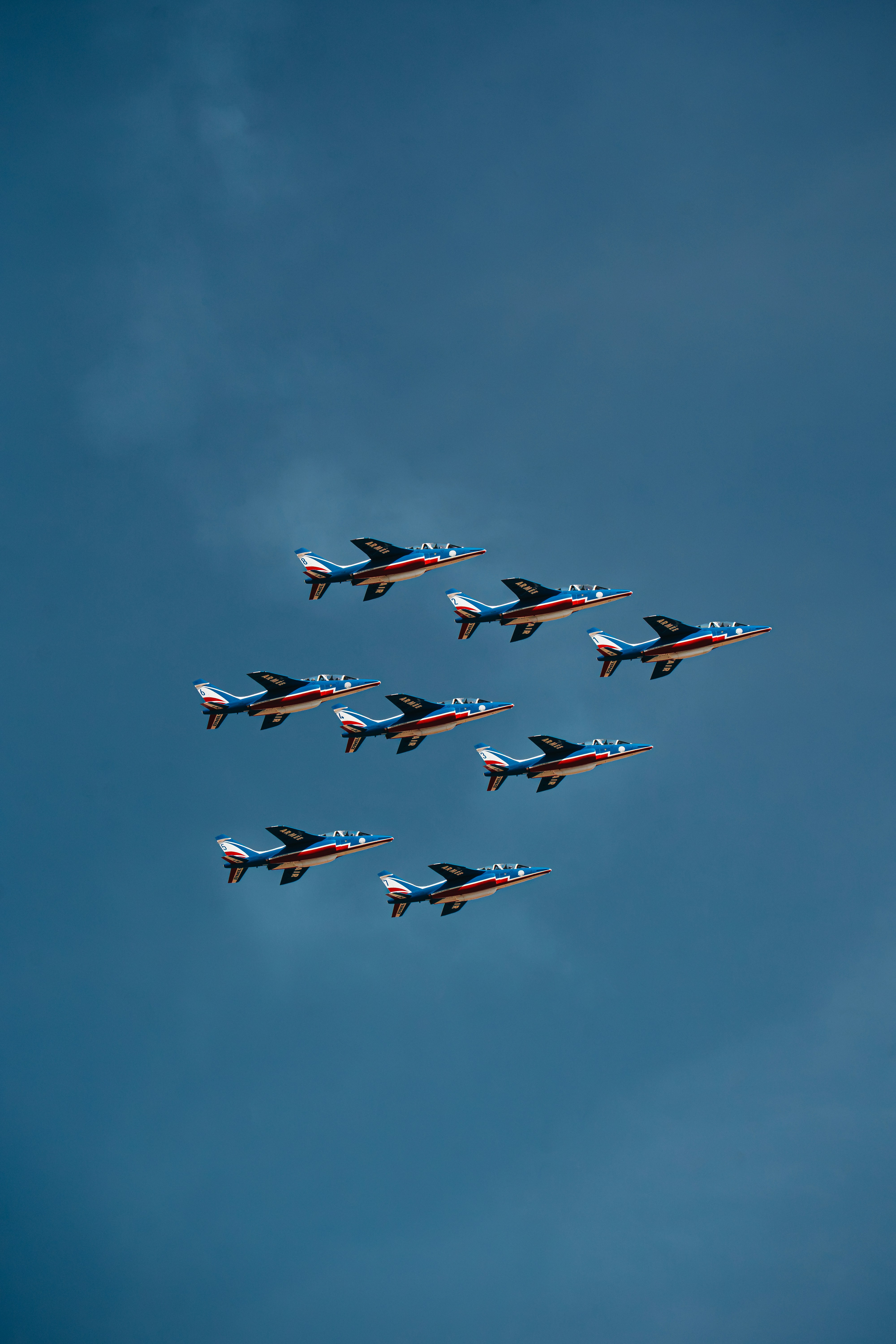 Acht blaue, weiße und rote Jetflugzeuge flogen in Formation gegen einen klaren Himmel
