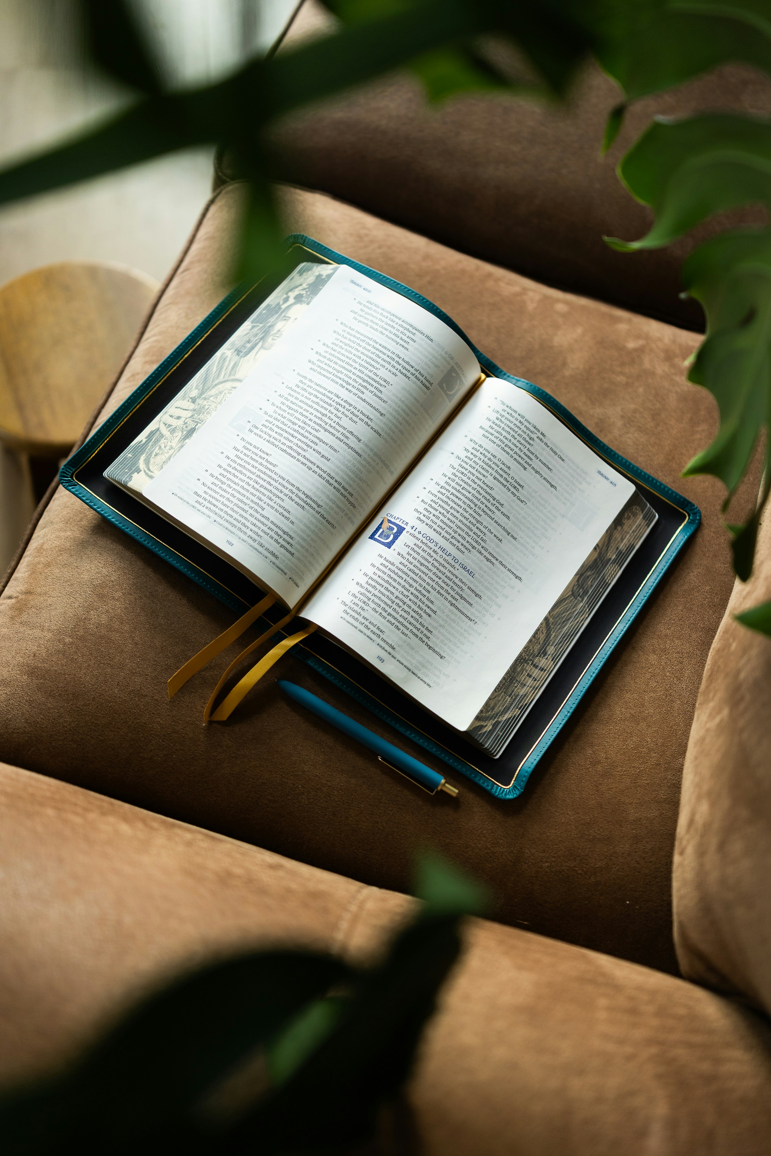 Una Bibbia aperta con pagine bordate d'oro su una poltrona di velluto marrone