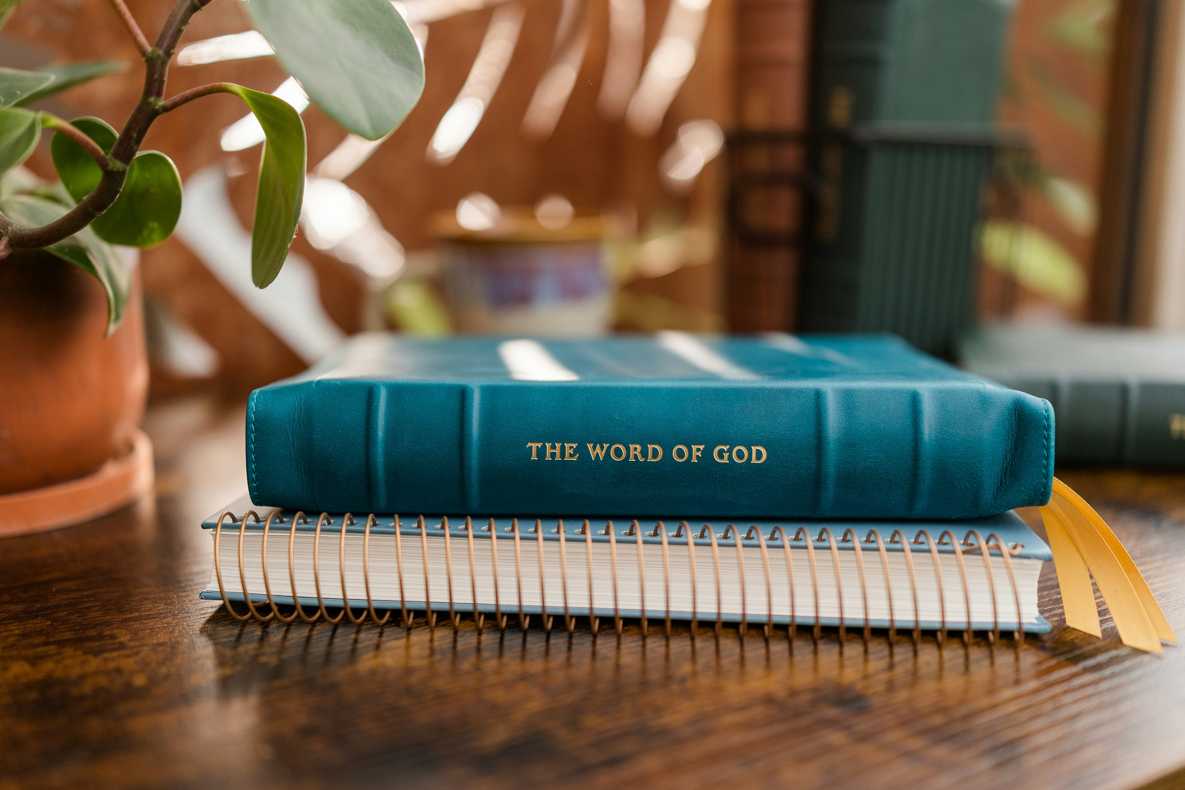 Un libro color teal intitolato LA PAROLA DI DIO che riposa su un quaderno a spirale