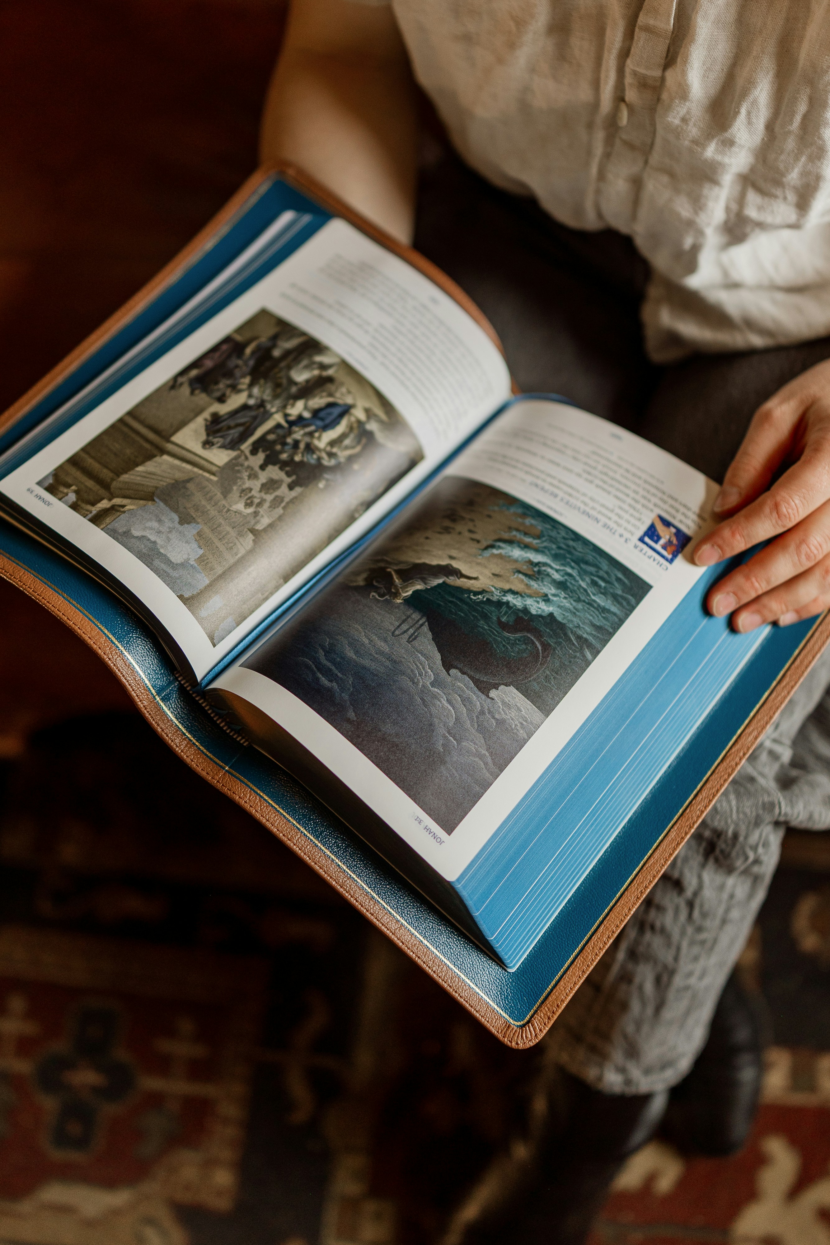 Una persona che tiene un libro aperto con illustrazioni di una balena in acqua