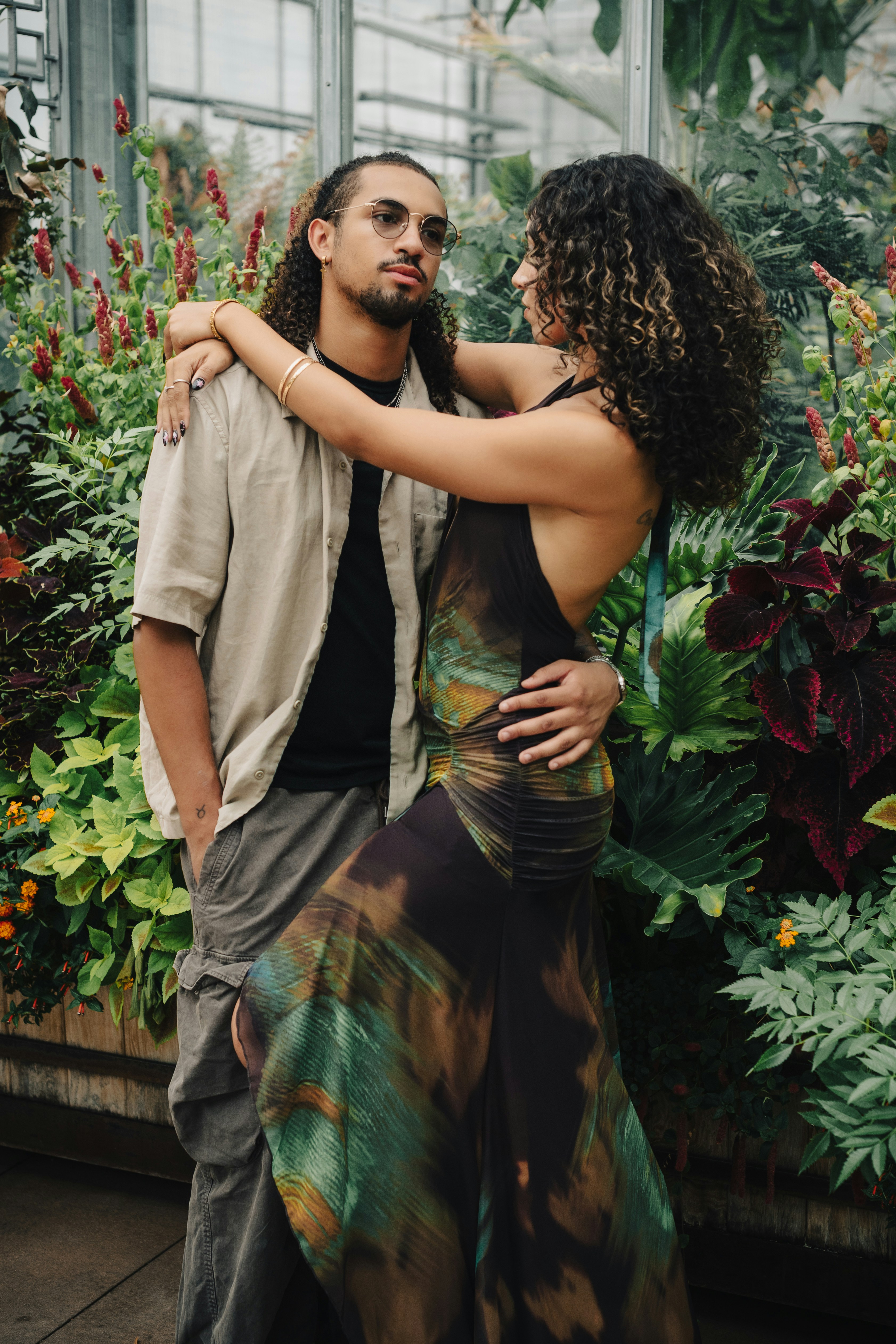 A man and a woman embracing in a lush greenhouse filled with tropical plants