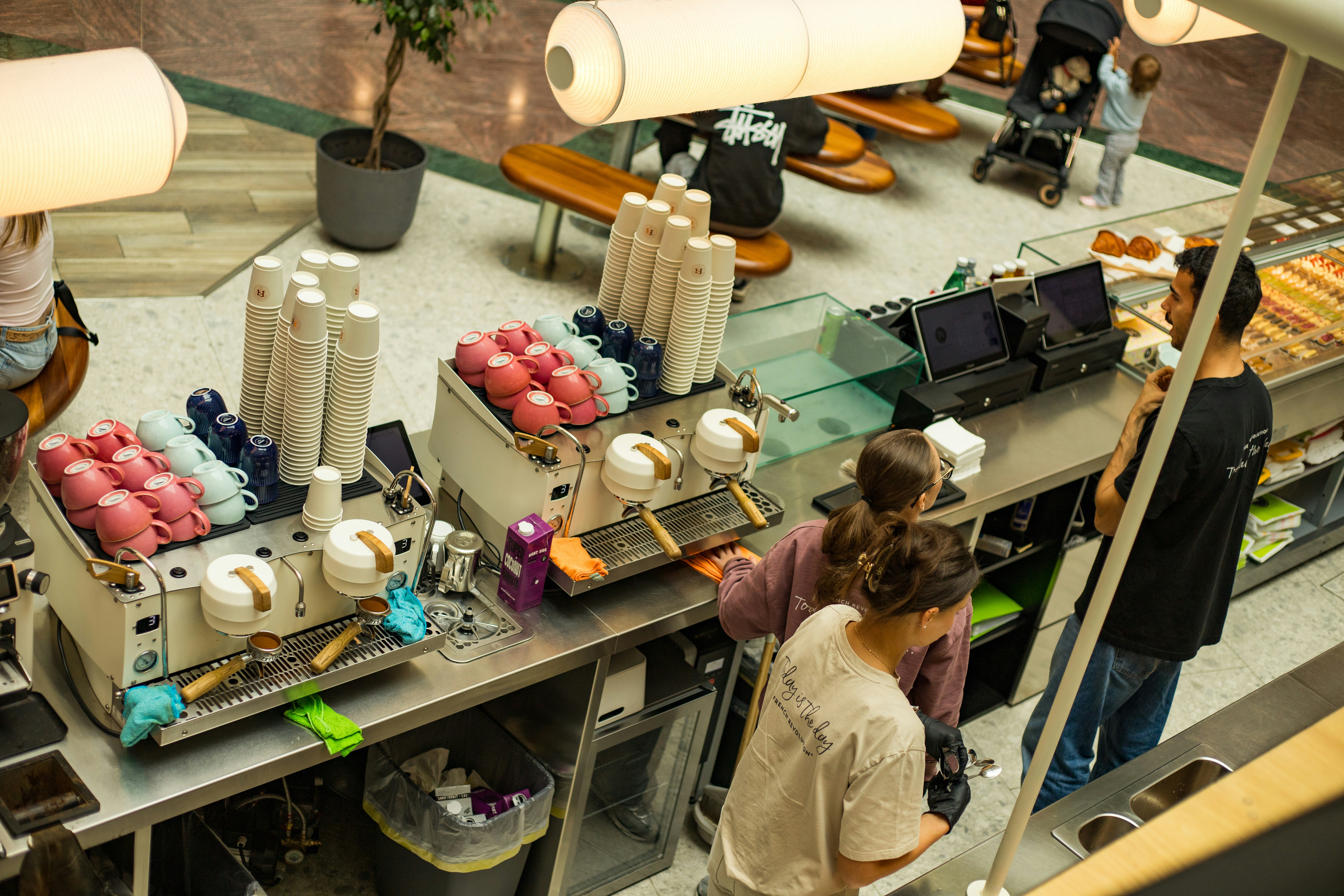 Baristas at work behind a busy coffee bar, with order screens on the counter