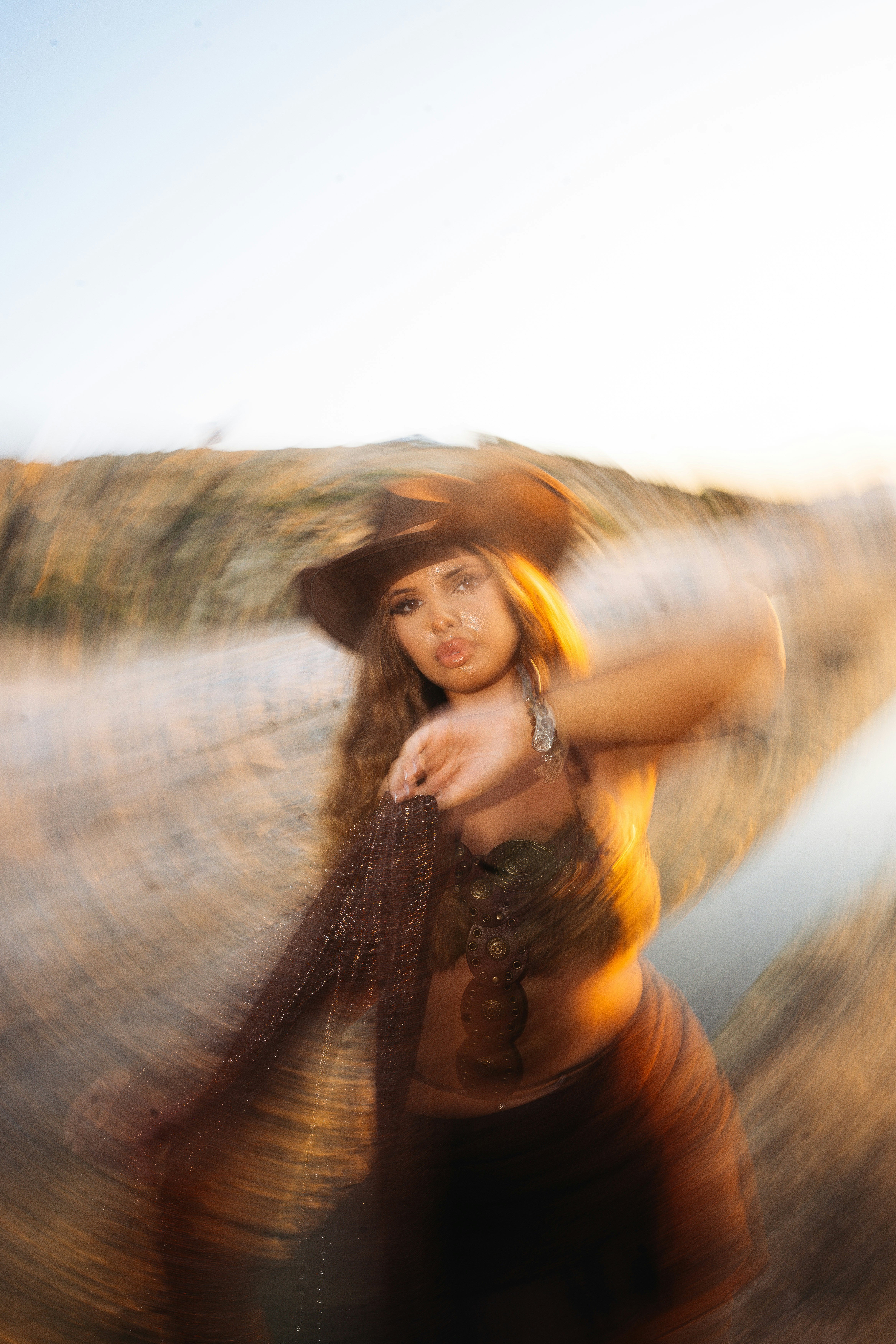 A woman in a brown cowboy hat and embellished top with a radial blur effect