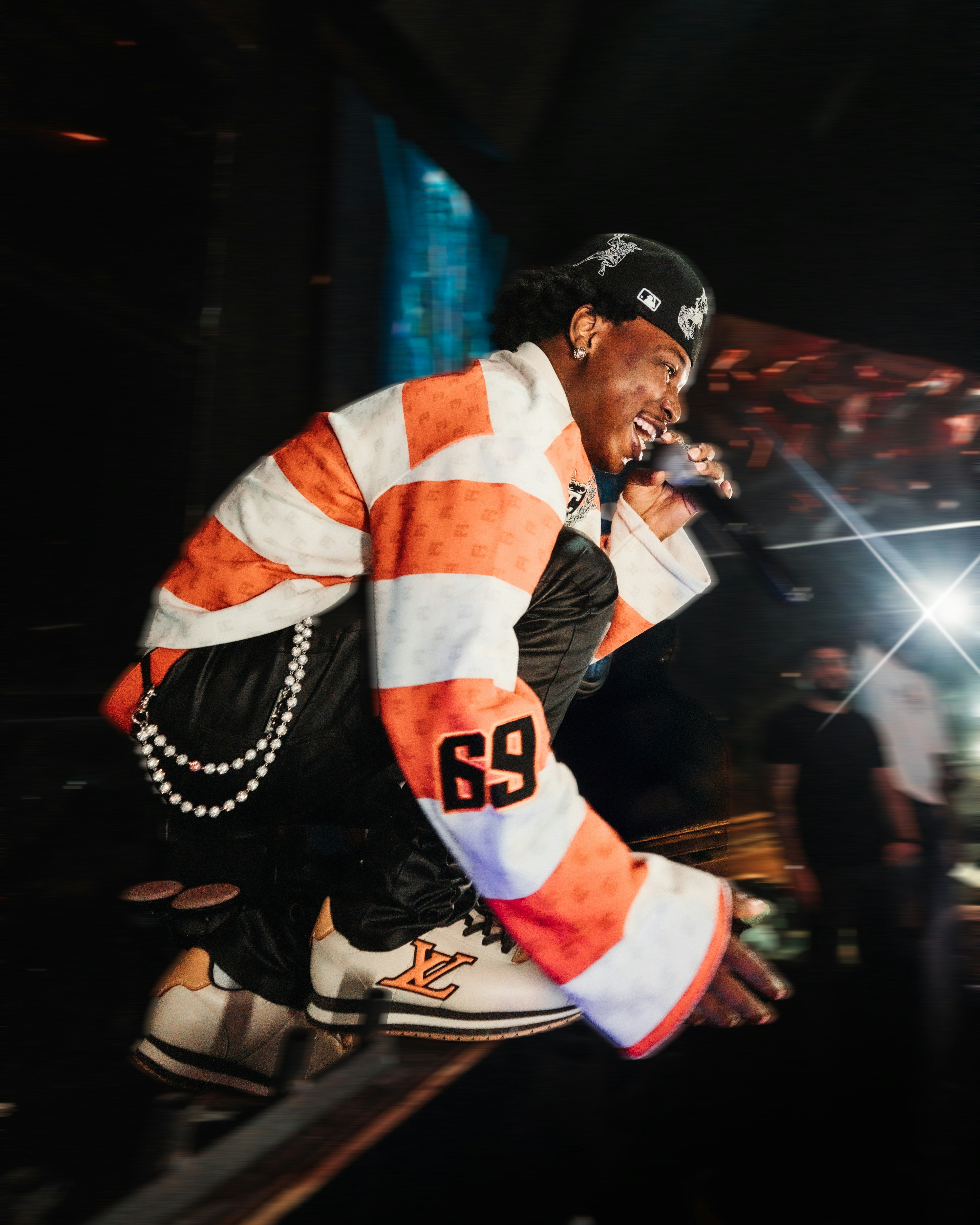 A person in an orange and white striped shirt crouching on a stage