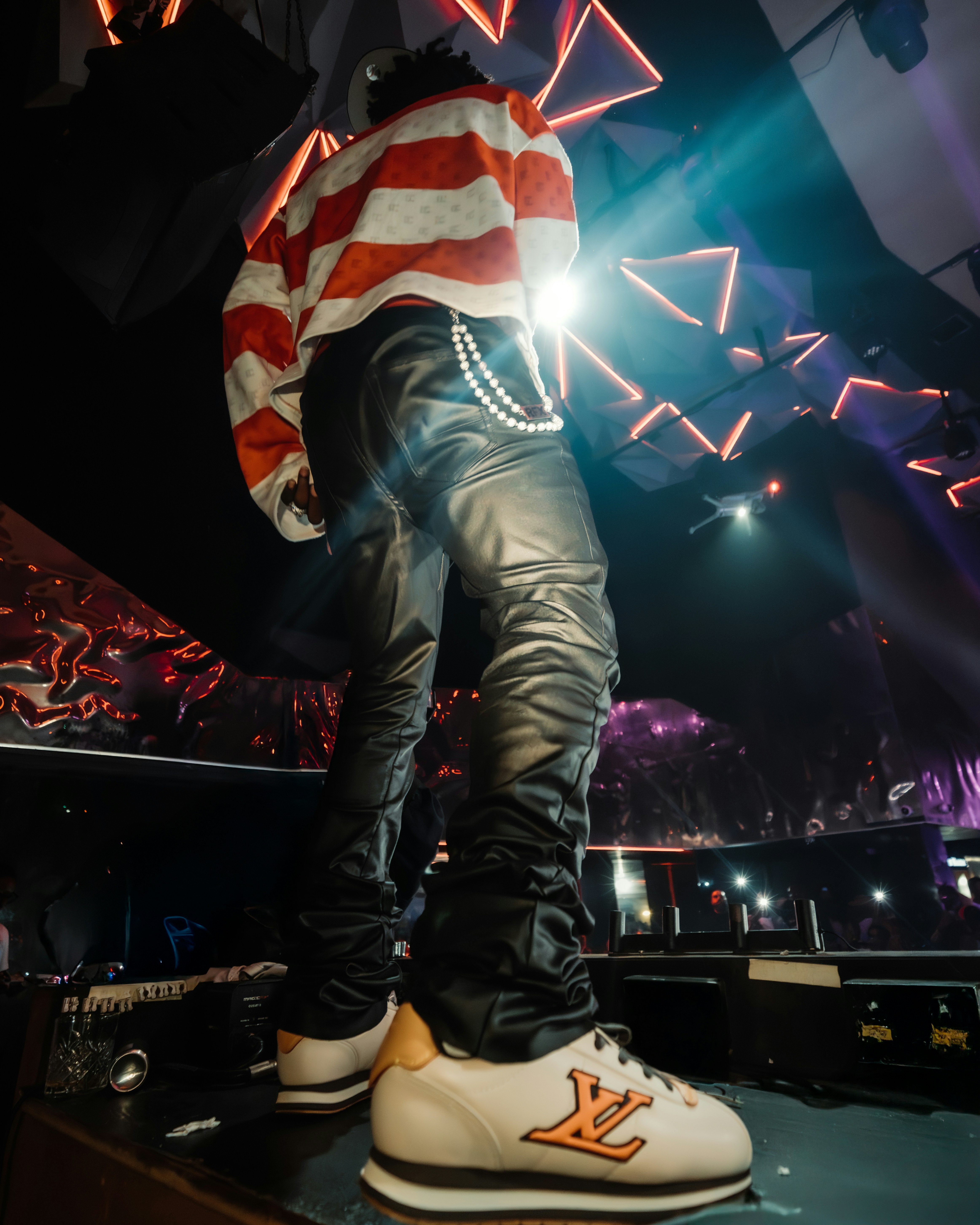 A person in a red and white striped shirt and black leather pants on stage