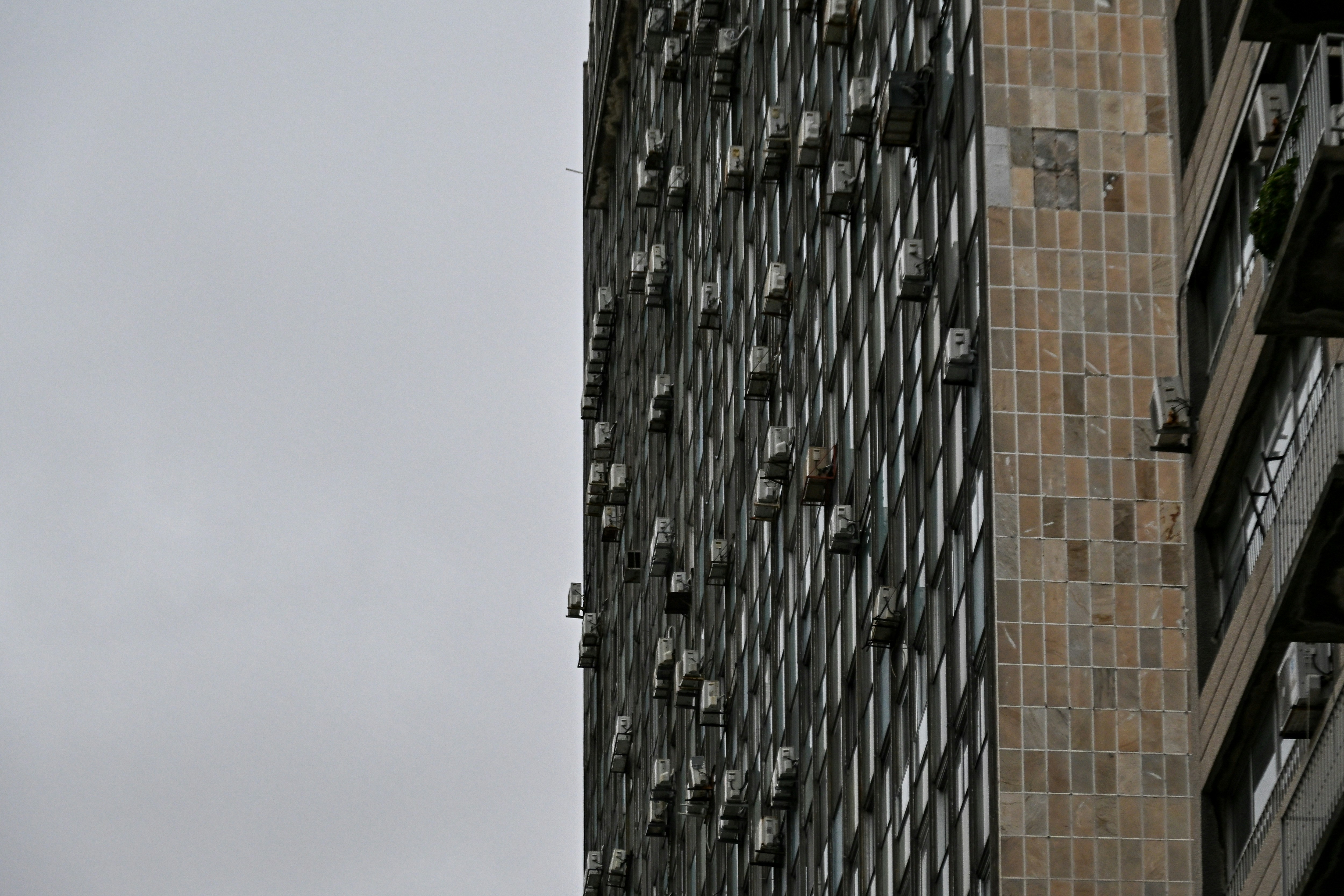 Une haute façade d’immeuble avec de nombreux climatiseurs par une journée grise
