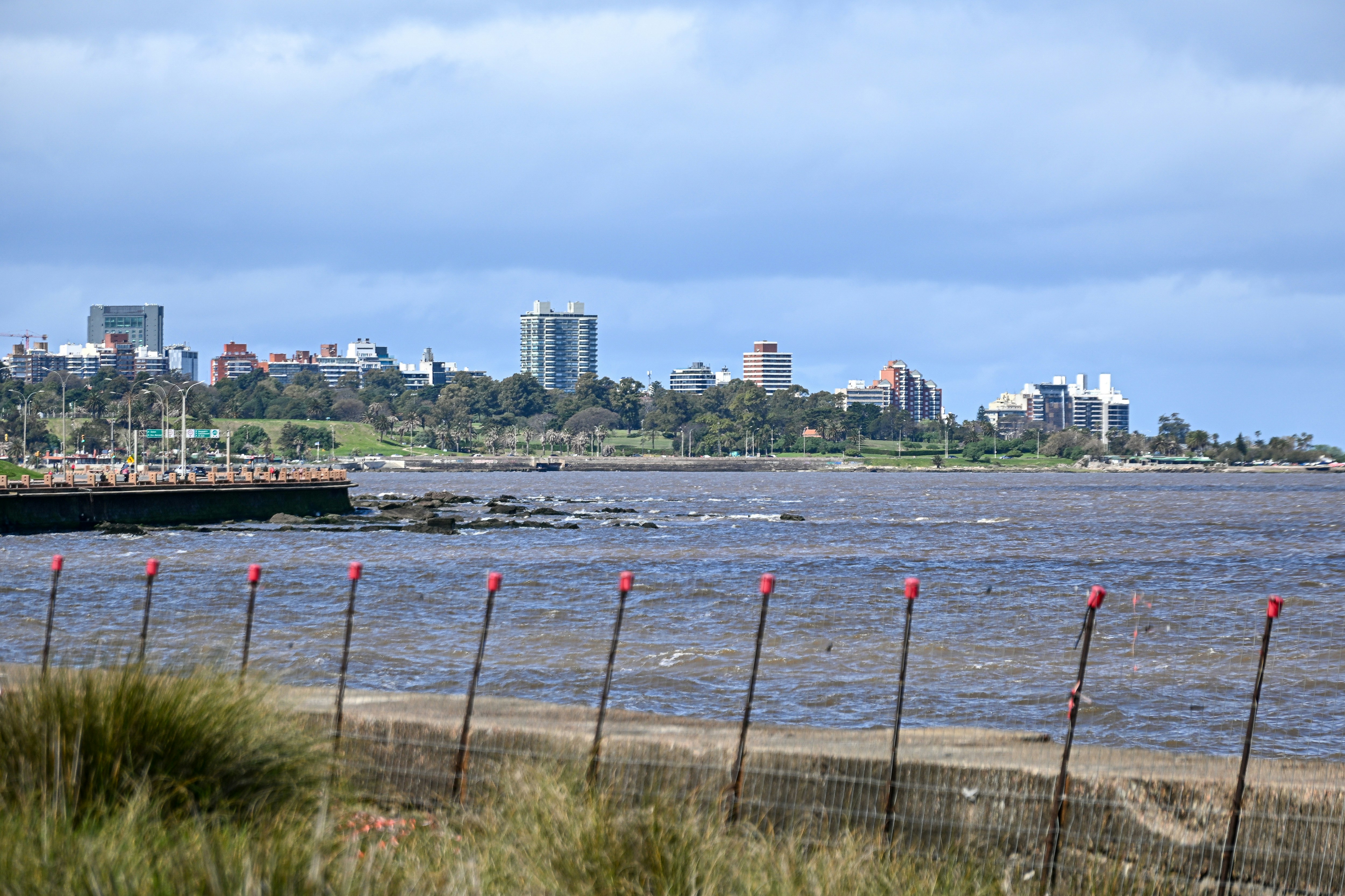 Une ligne d’horizon d’une ville côtière de l’autre côté d’une large rivière avec une clôture au premier plan