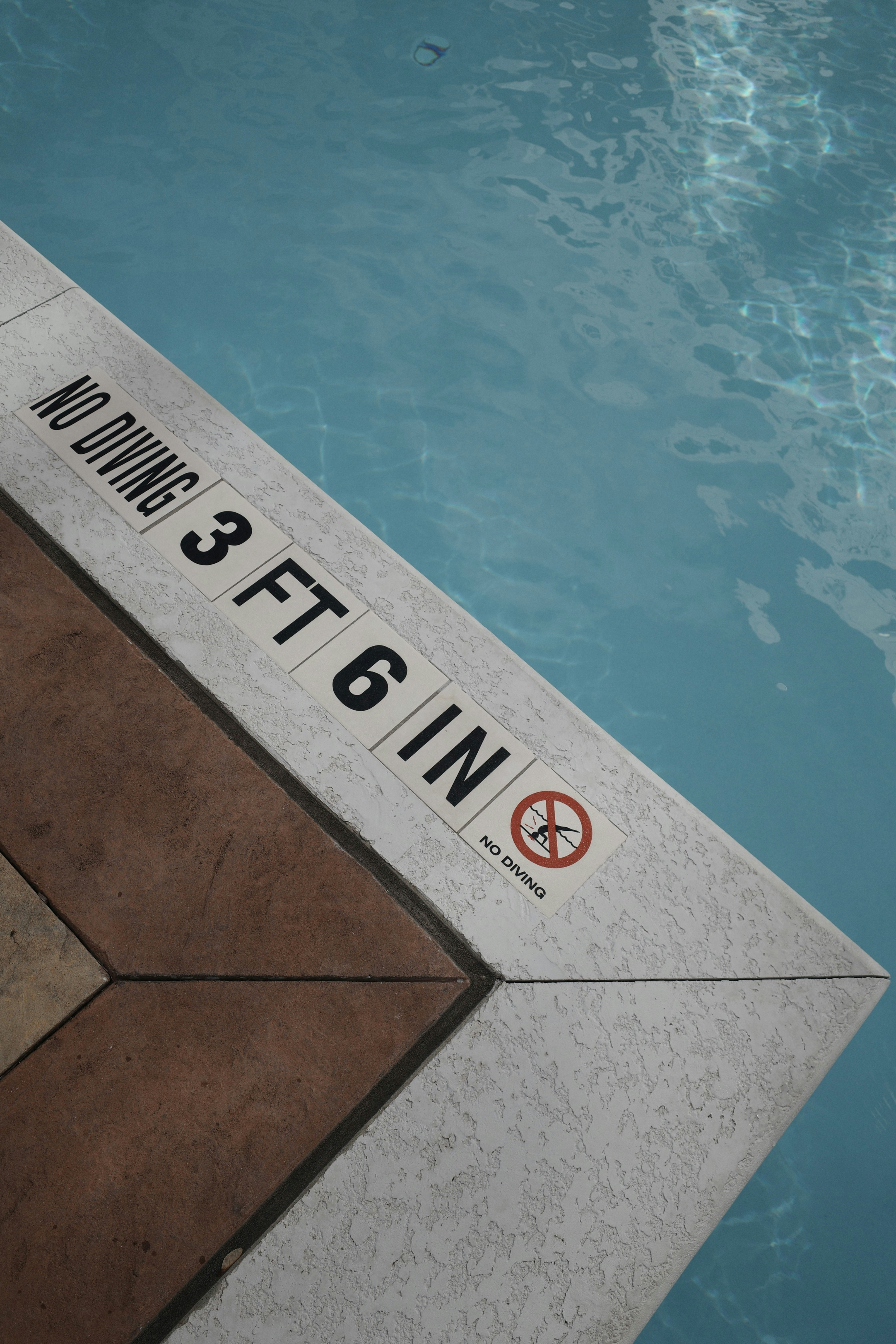 A swimming pool edge with a sign reading NO DIVING 3 FT 6 IN