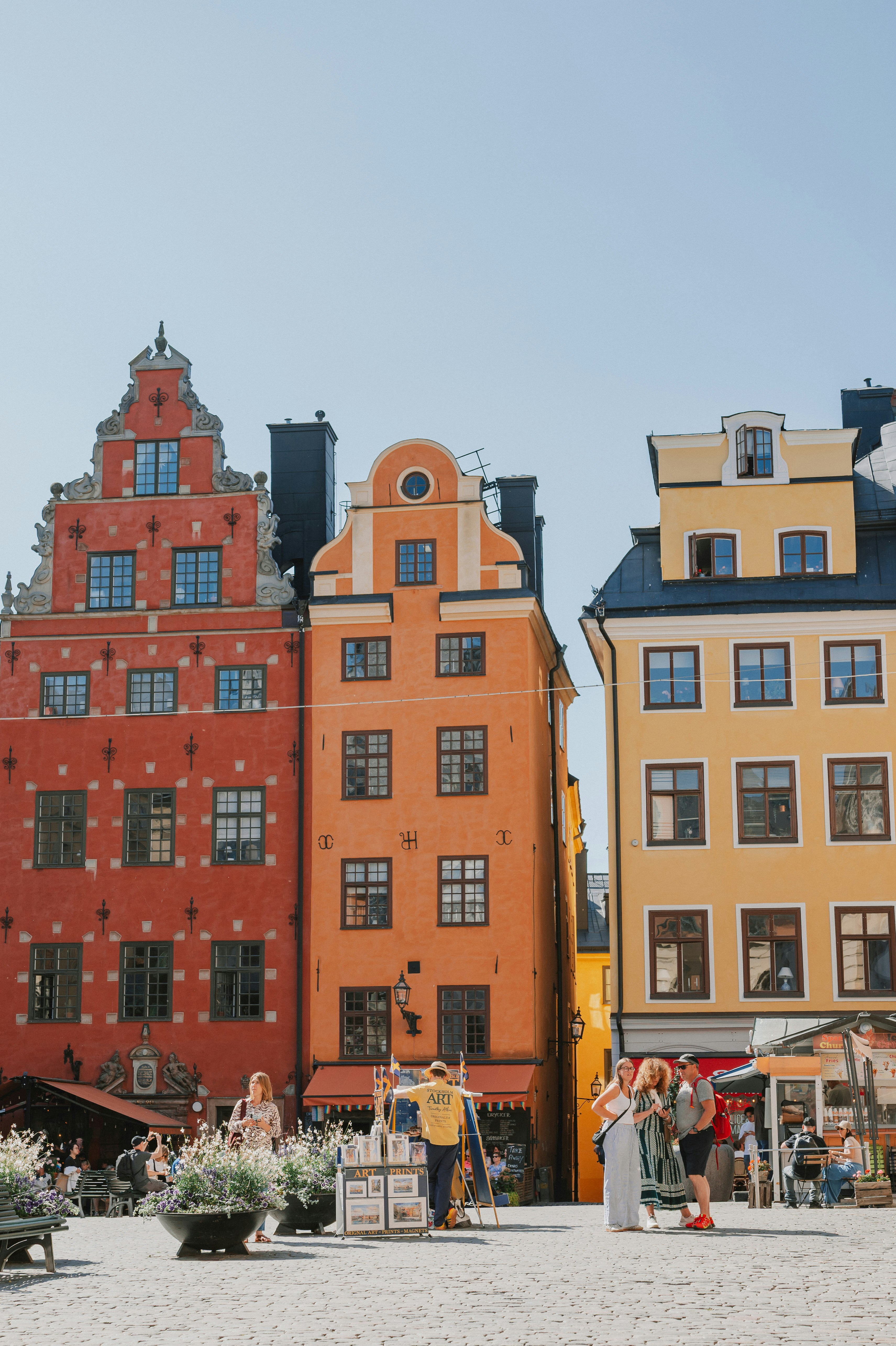 People in a cobblestone square before colorful historic buildings in Stockholm, Sweden