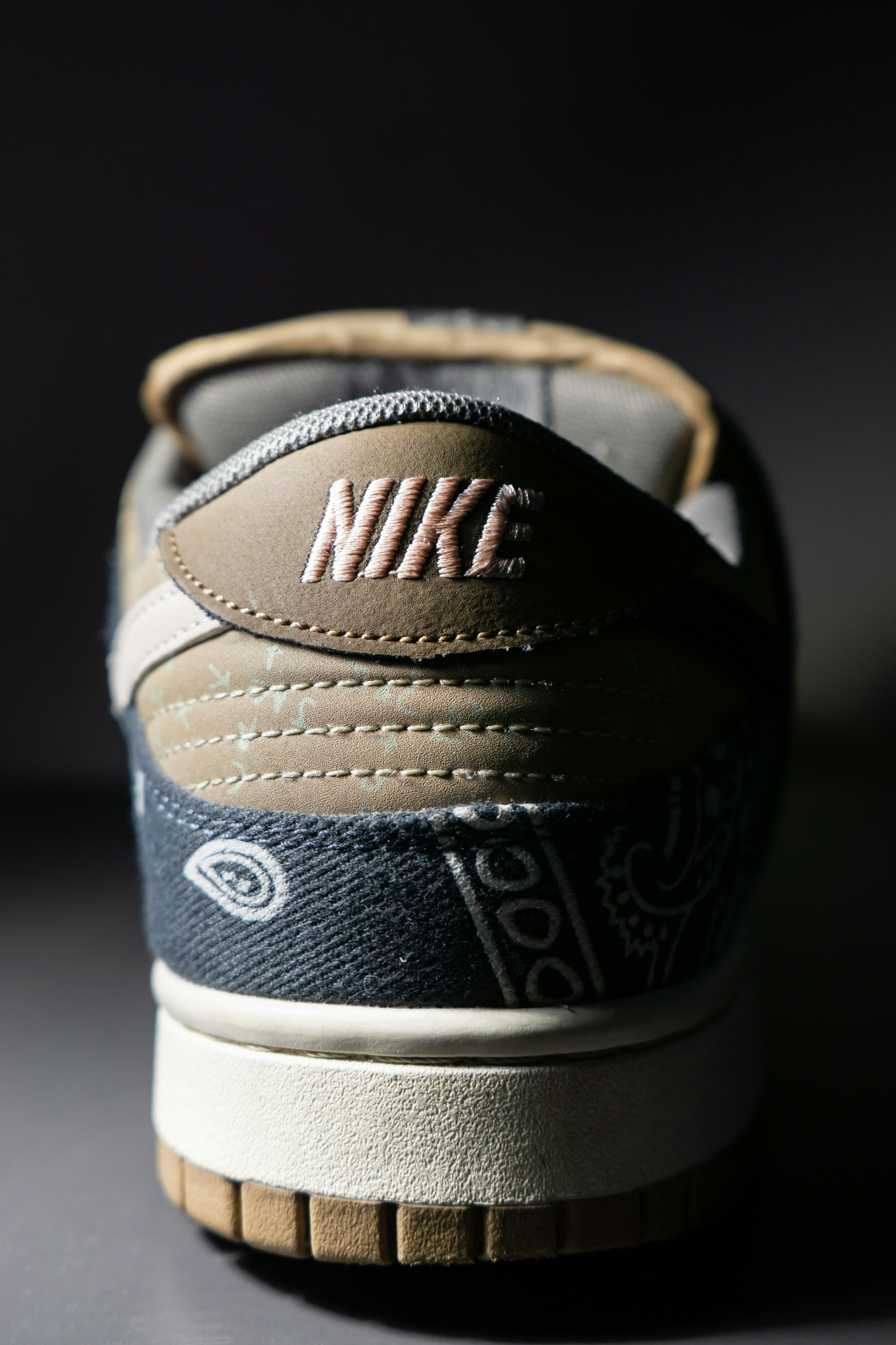 The heel of a sneaker with paisley patterned fabric and embroidered text