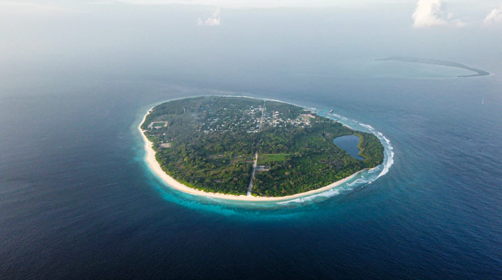 An aerial view of a tropical island surrounded by deep blue ocean