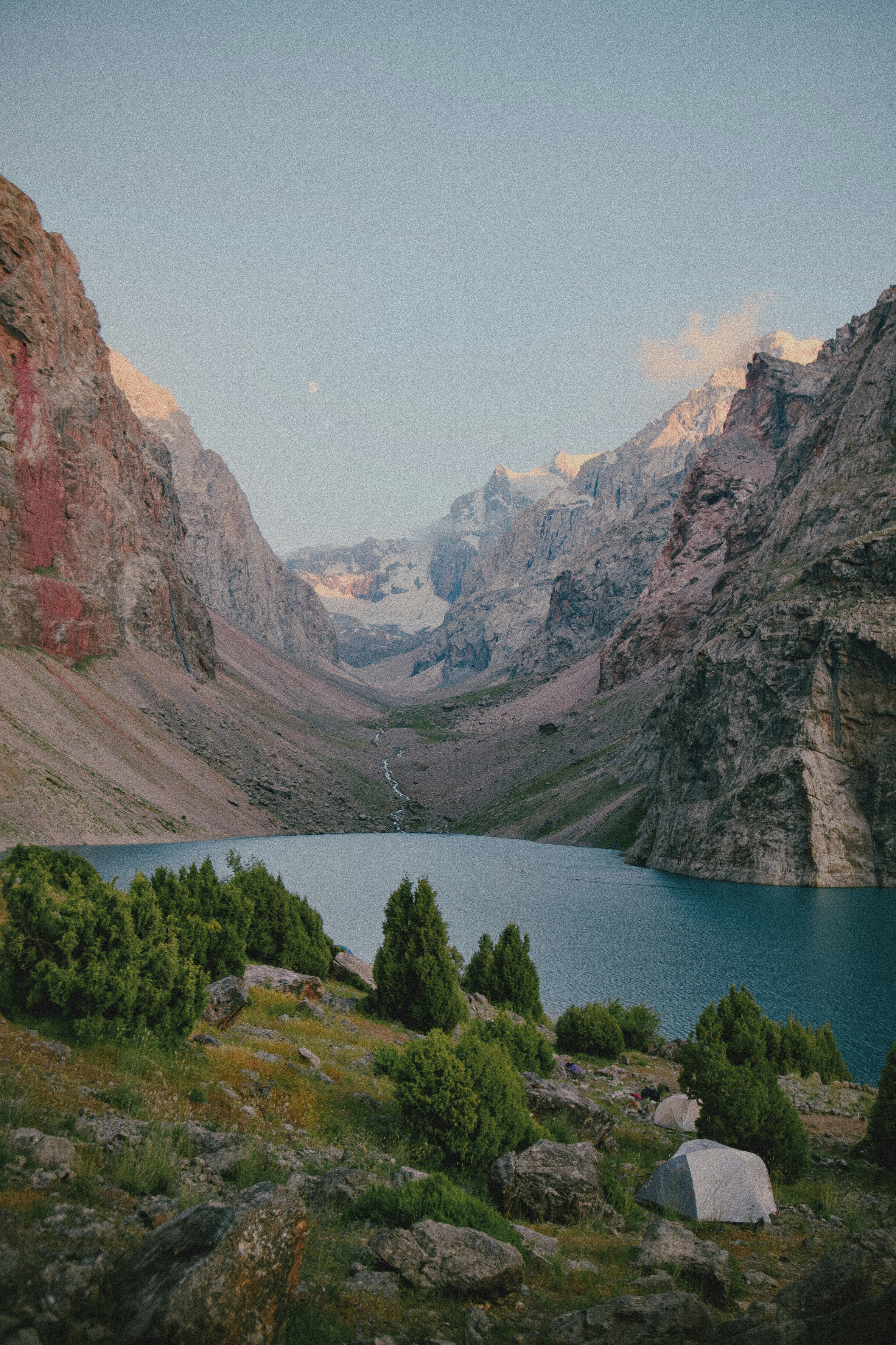 A blue alpine lake surrounded by steep rocky mountains and small green trees
