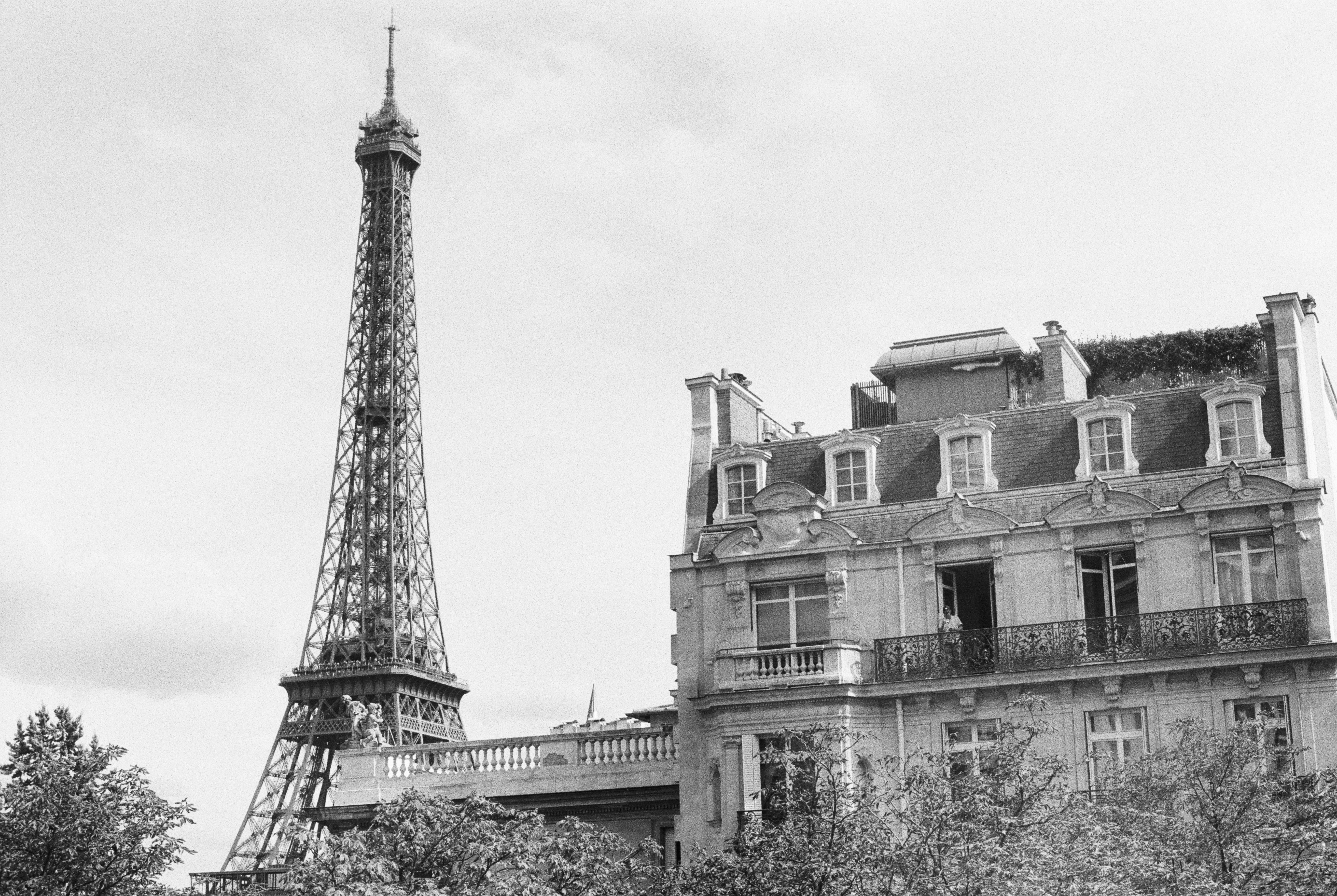 The Eiffel Tower rising above a classic stone building with balconies in Paris