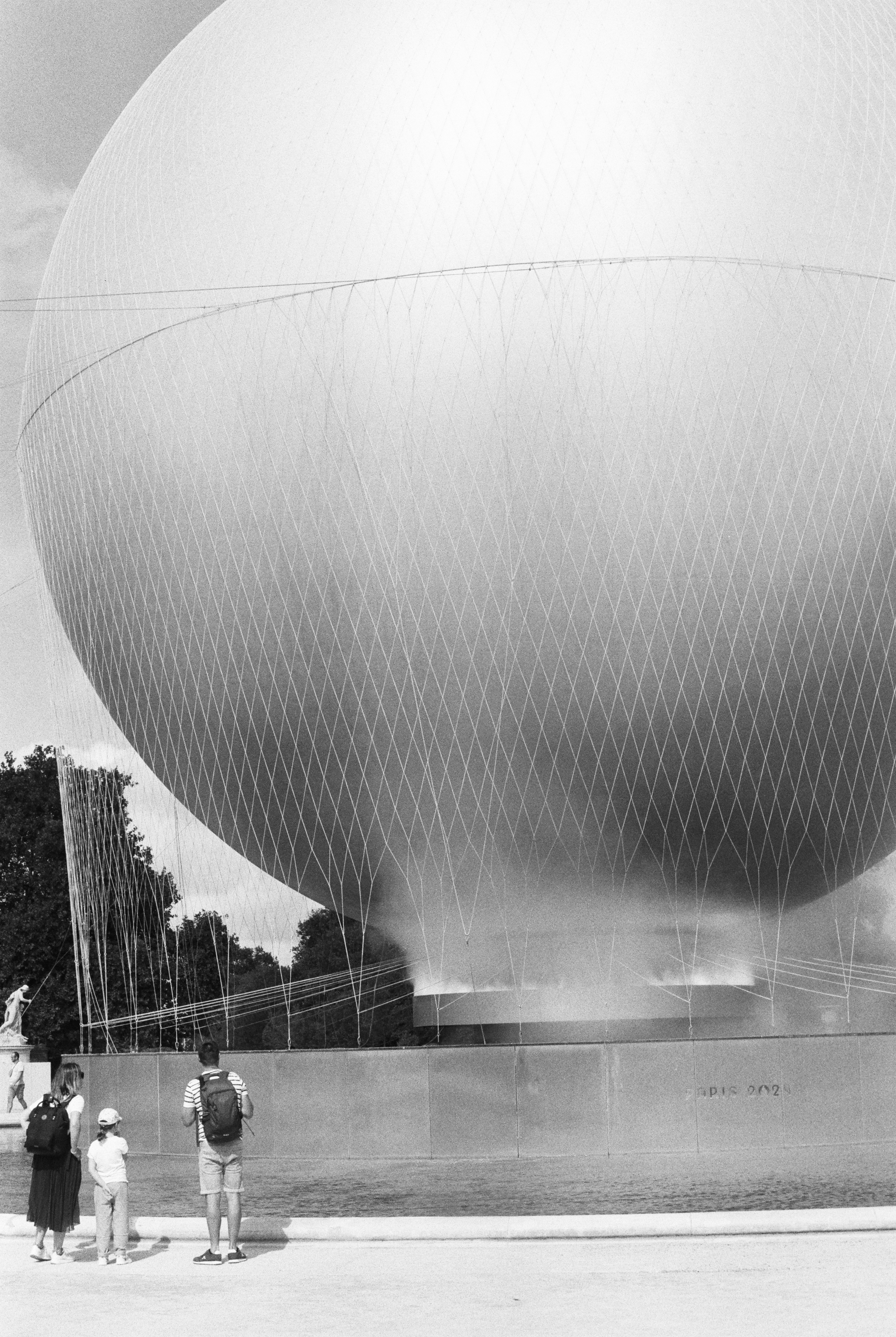 A family looking at a large tethered helium balloon in a park
