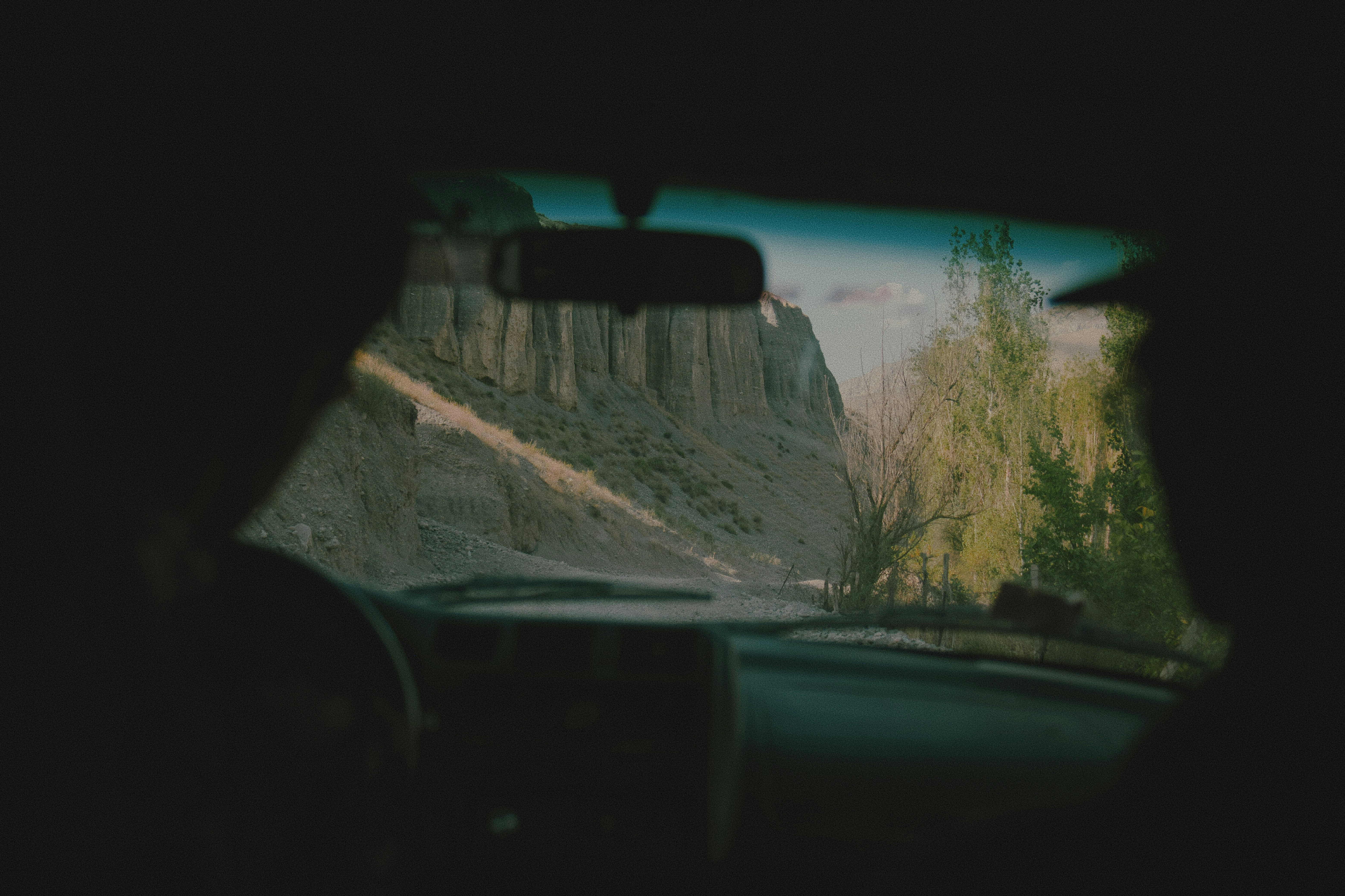 View from inside a car toward a rocky canyon and green trees