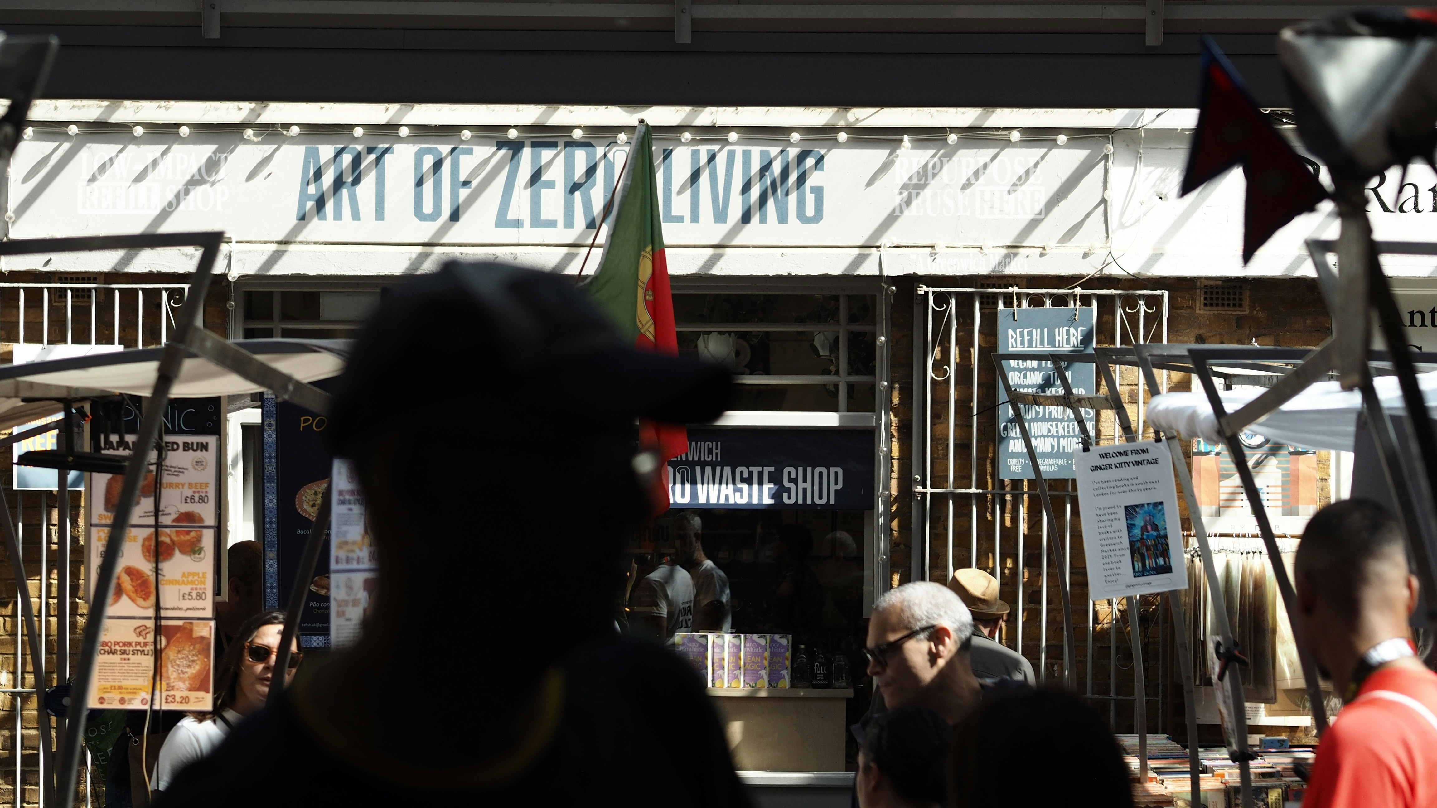 People browsing a market stall in front of a shop named Art of Zero Living