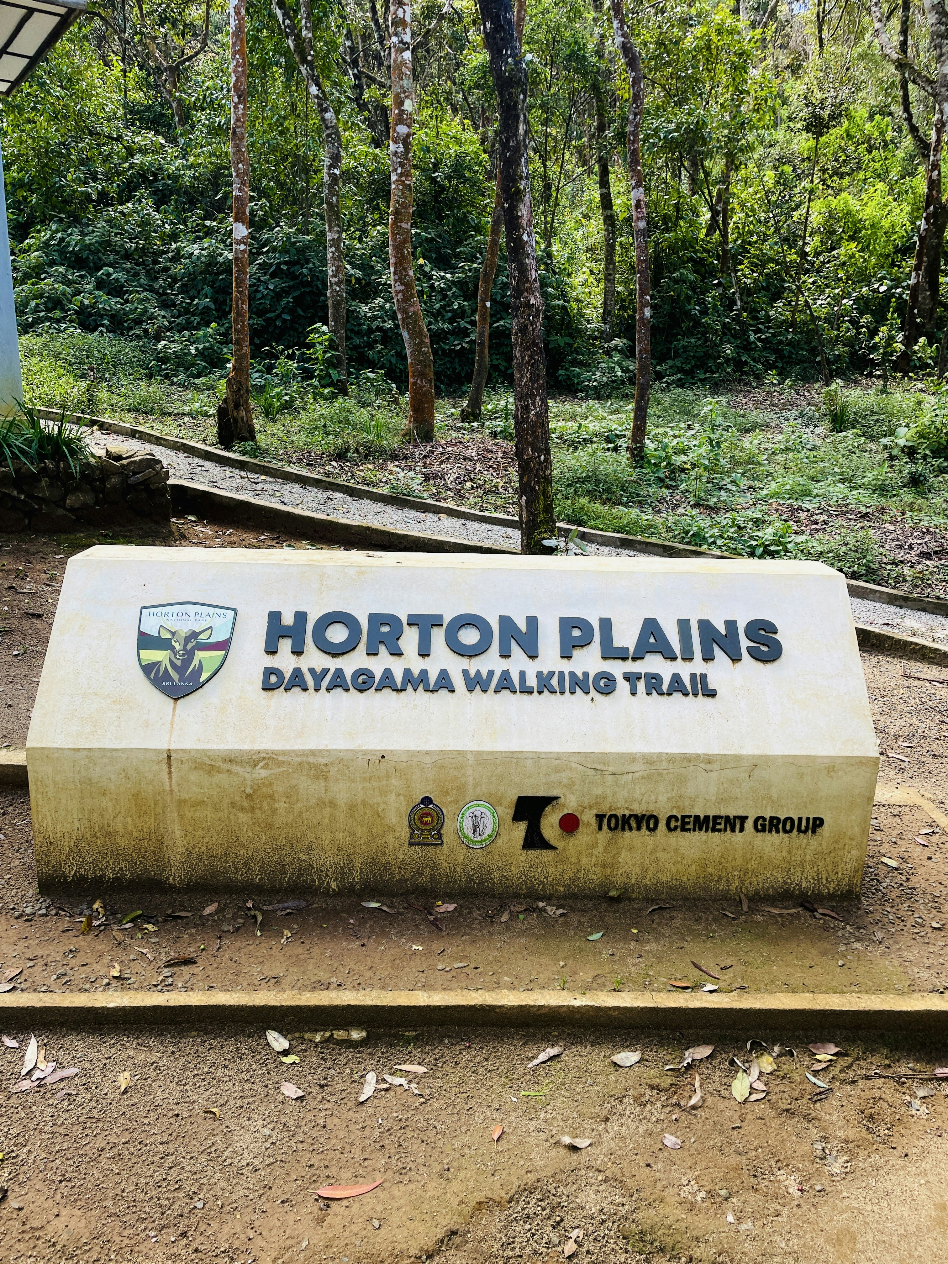 A concrete sign for the Horton Plains Dayagama walking trail in a forest