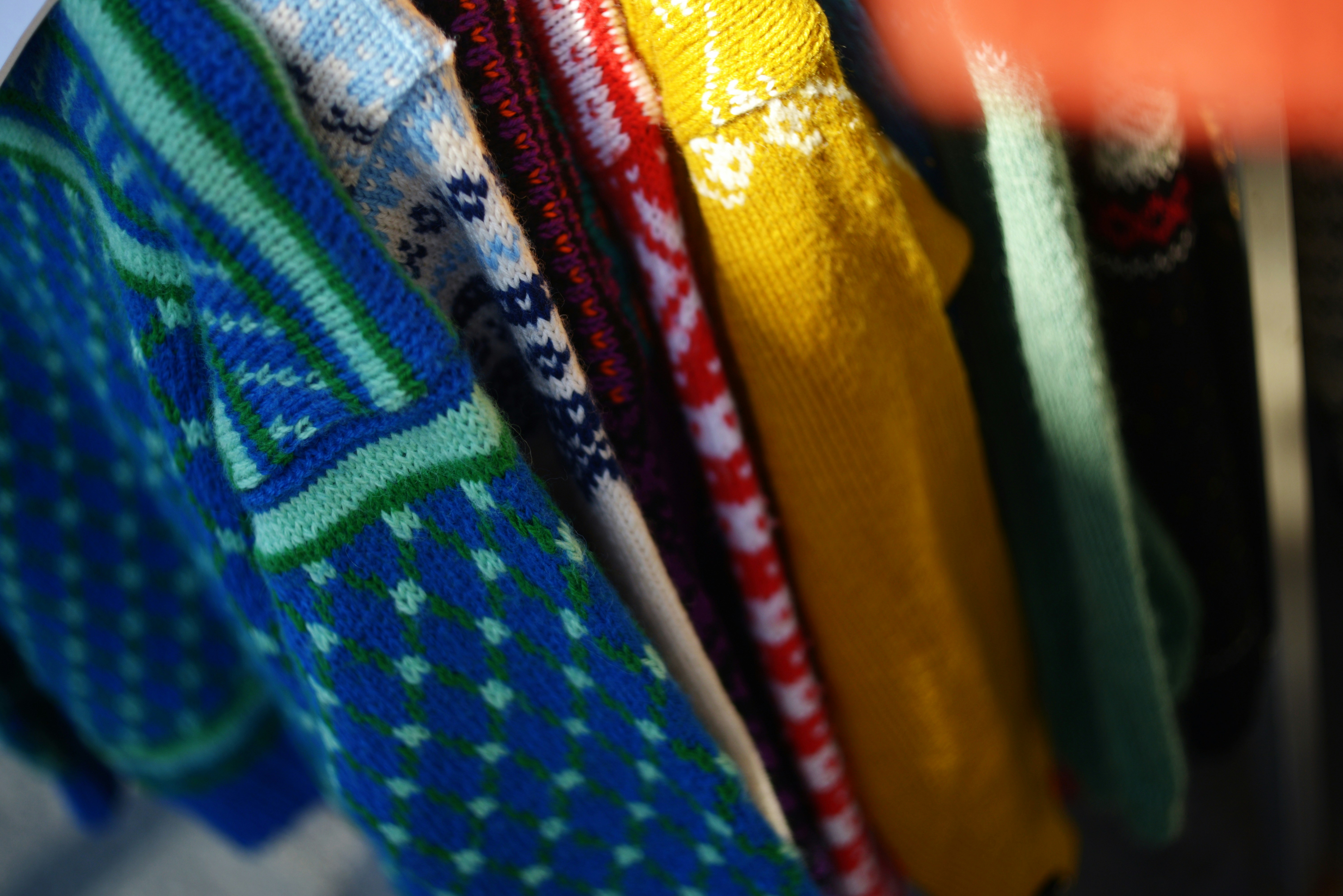 A row of colorful patterned knit sweaters hanging on a rack