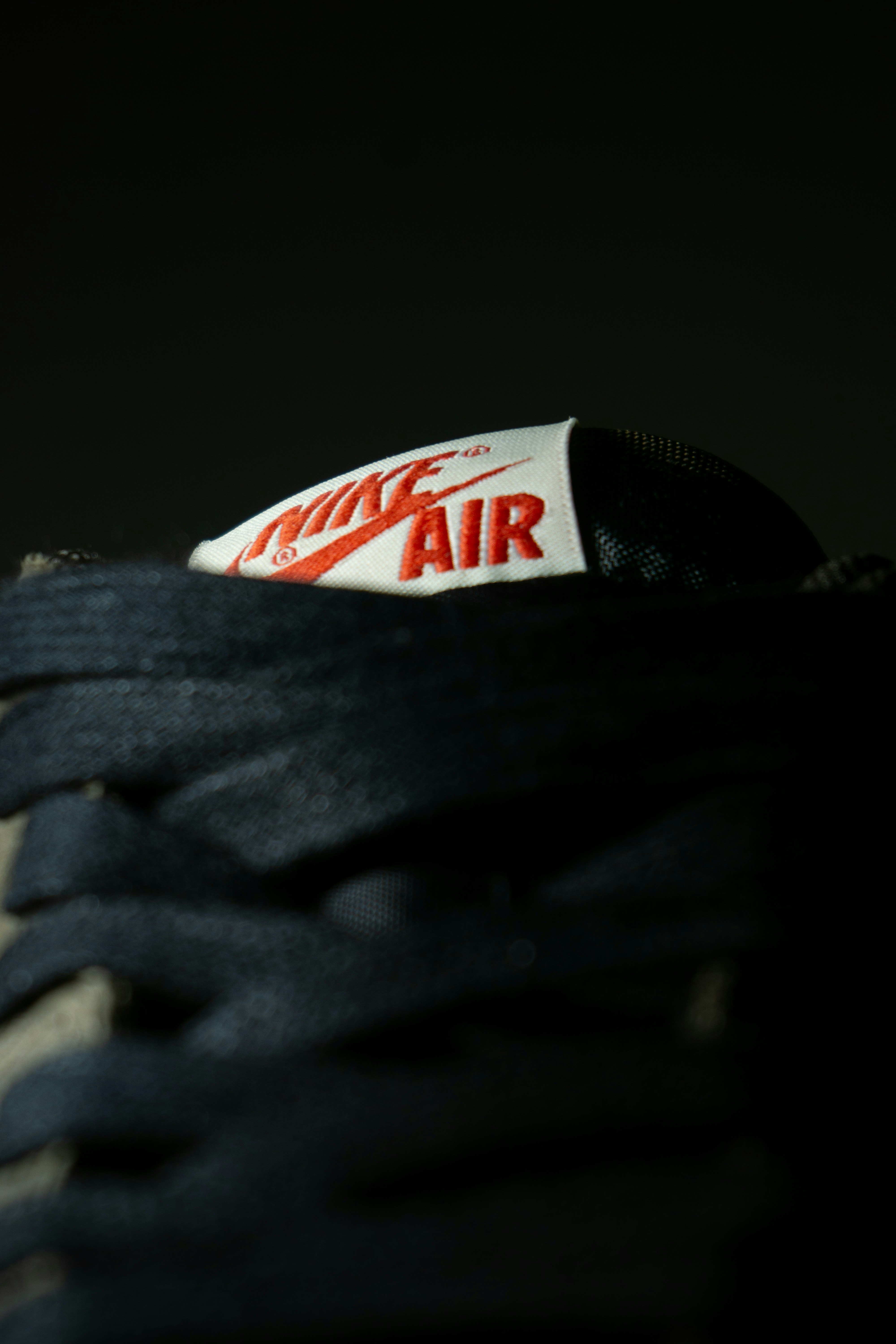 A white tongue tag with red Nike Air text on a black sneaker