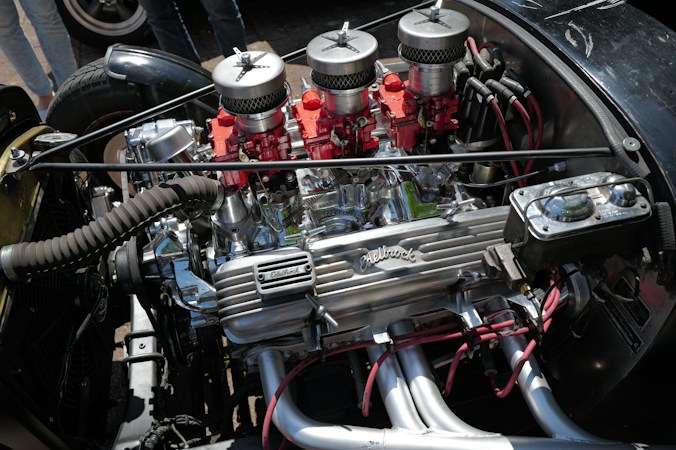 A chrome hot rod engine with three red carburetors, the kind of custom engine work car fans come to see up close at Henderson Hot Rod Days