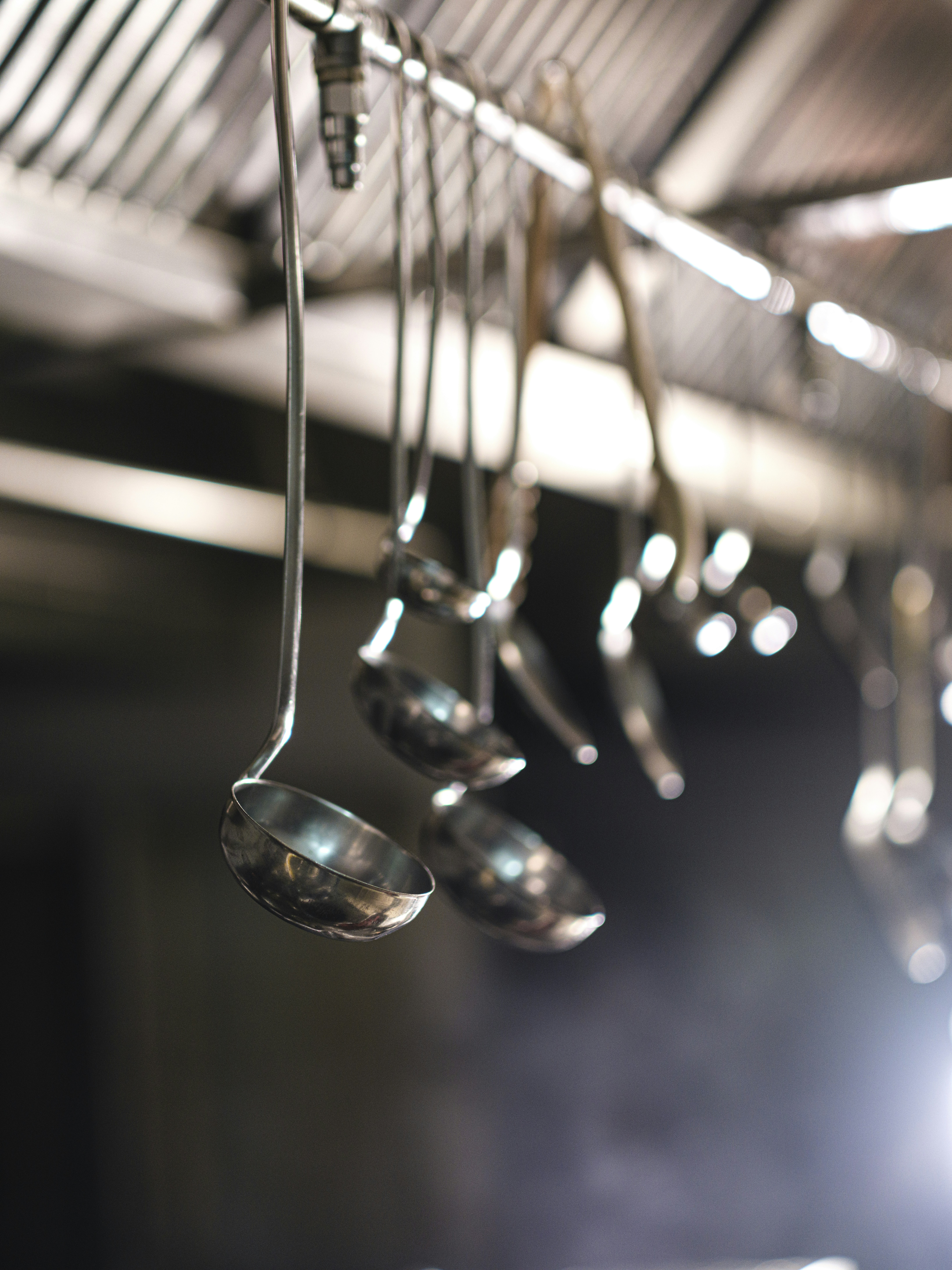 Metal ladles hanging from a rack in a professional kitchen