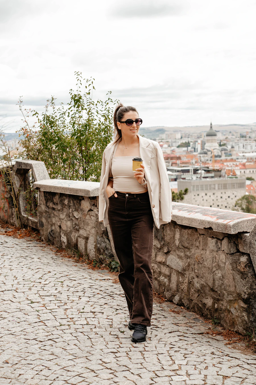 Mujer con blazer y café camino del trabajo
