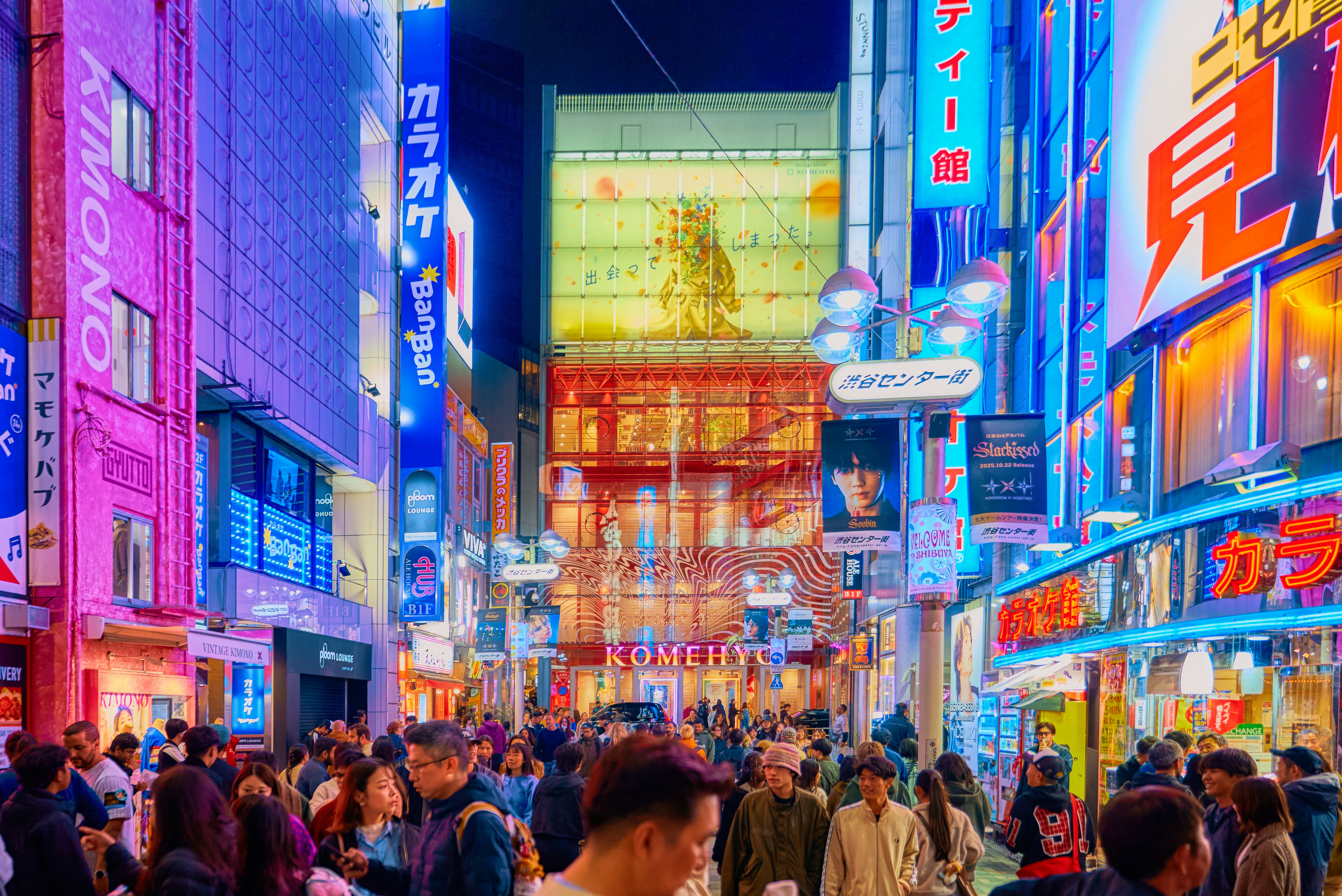 A crowd of people walking on a neon-lit street in Shibuya, Tokyo