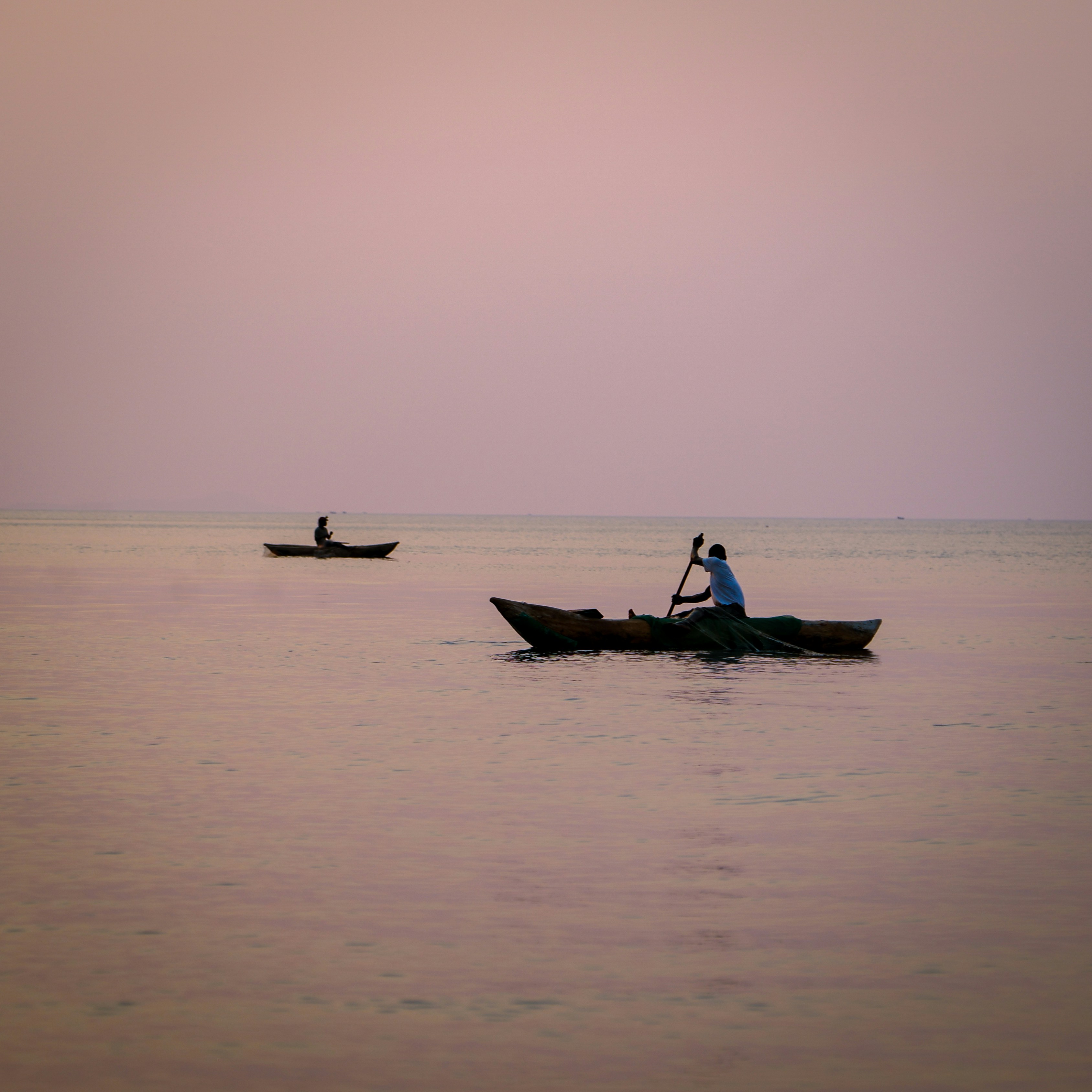 Fishermen in dugout canoes on the lake at dusk