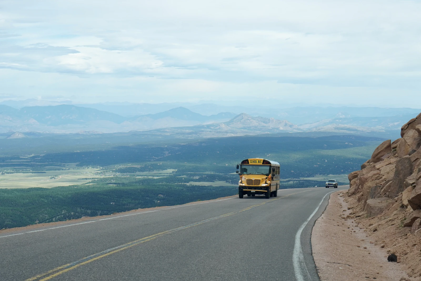 A school bus on a mountain road above a wide valley