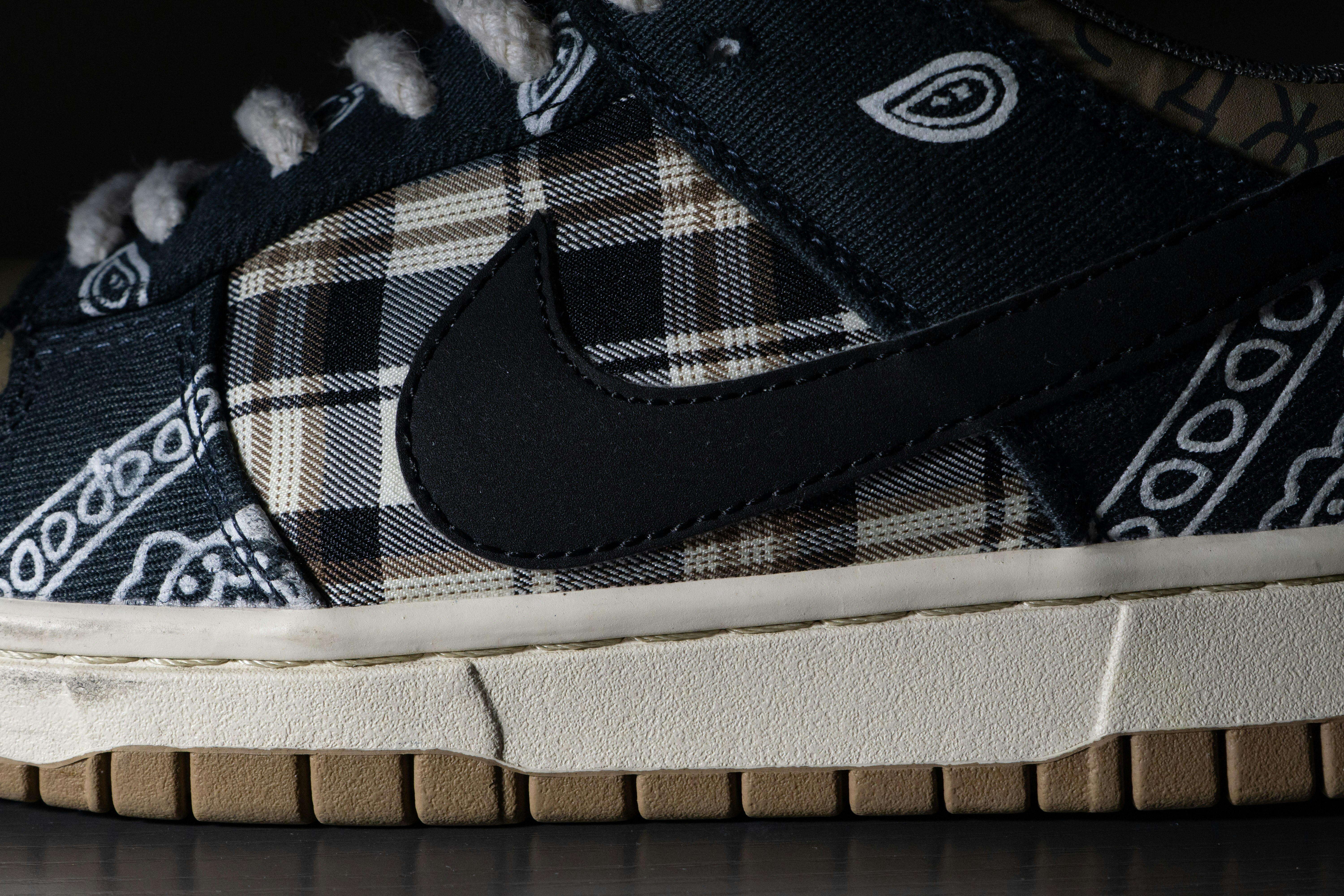 A sneaker with a black paisley pattern and brown plaid fabric side panel