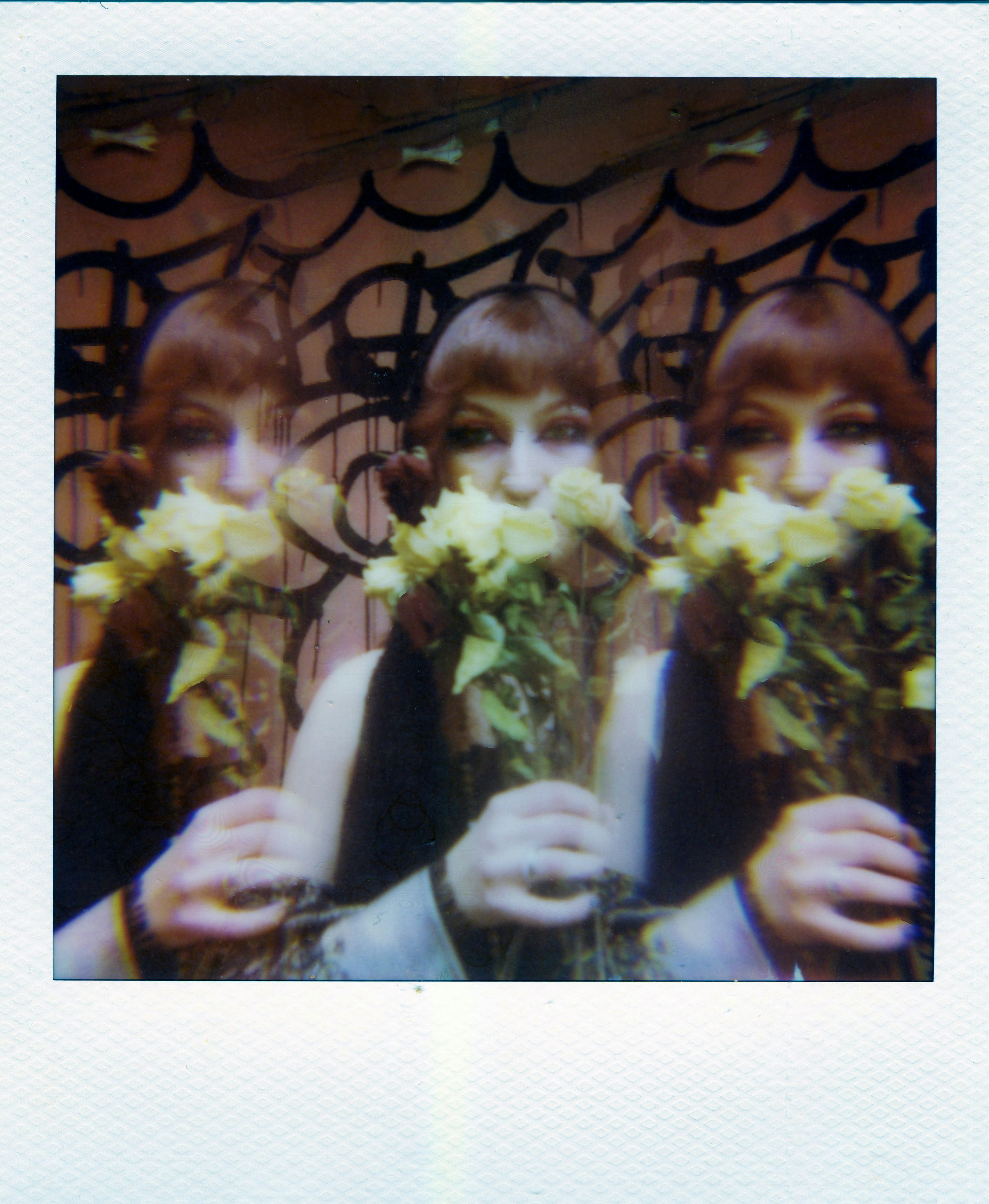 A triple exposure of a person holding yellow flowers against a graffiti wall