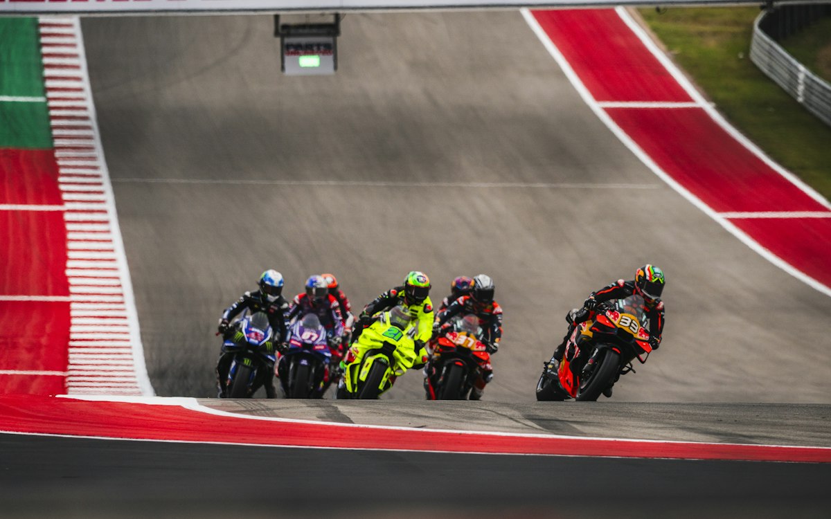 Groupe de motos de course penchées dans un virage sur un circuit asphalté